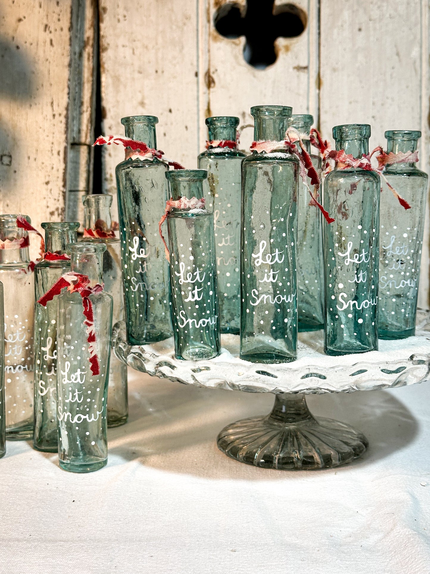 A beautiful Victorian cylinder bottle painted with a Christmas quote “Let it Snow”