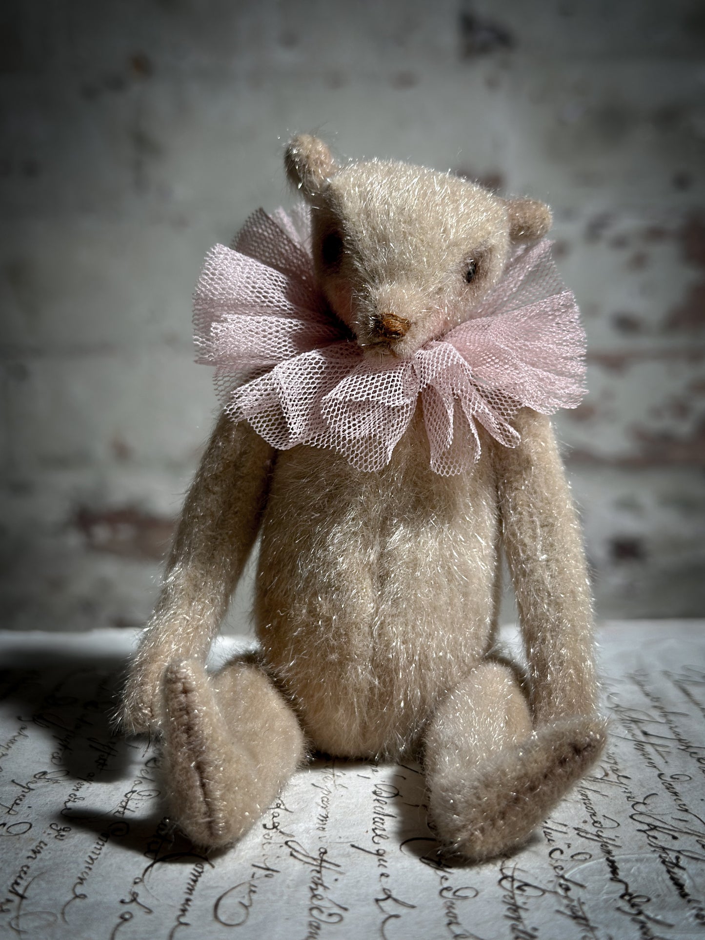 A beautiful hand made jointed collector’s teddy bear with antique pink tulle ruffle