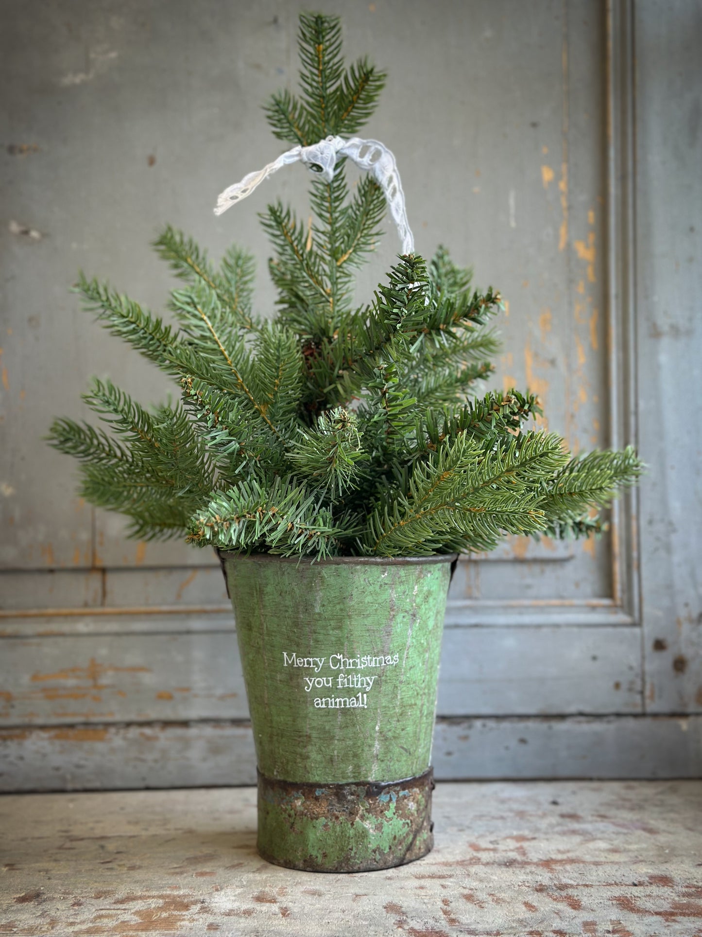 A Recycled Metal Mini Christmas Tree Bucket With A Hand Painted Quote