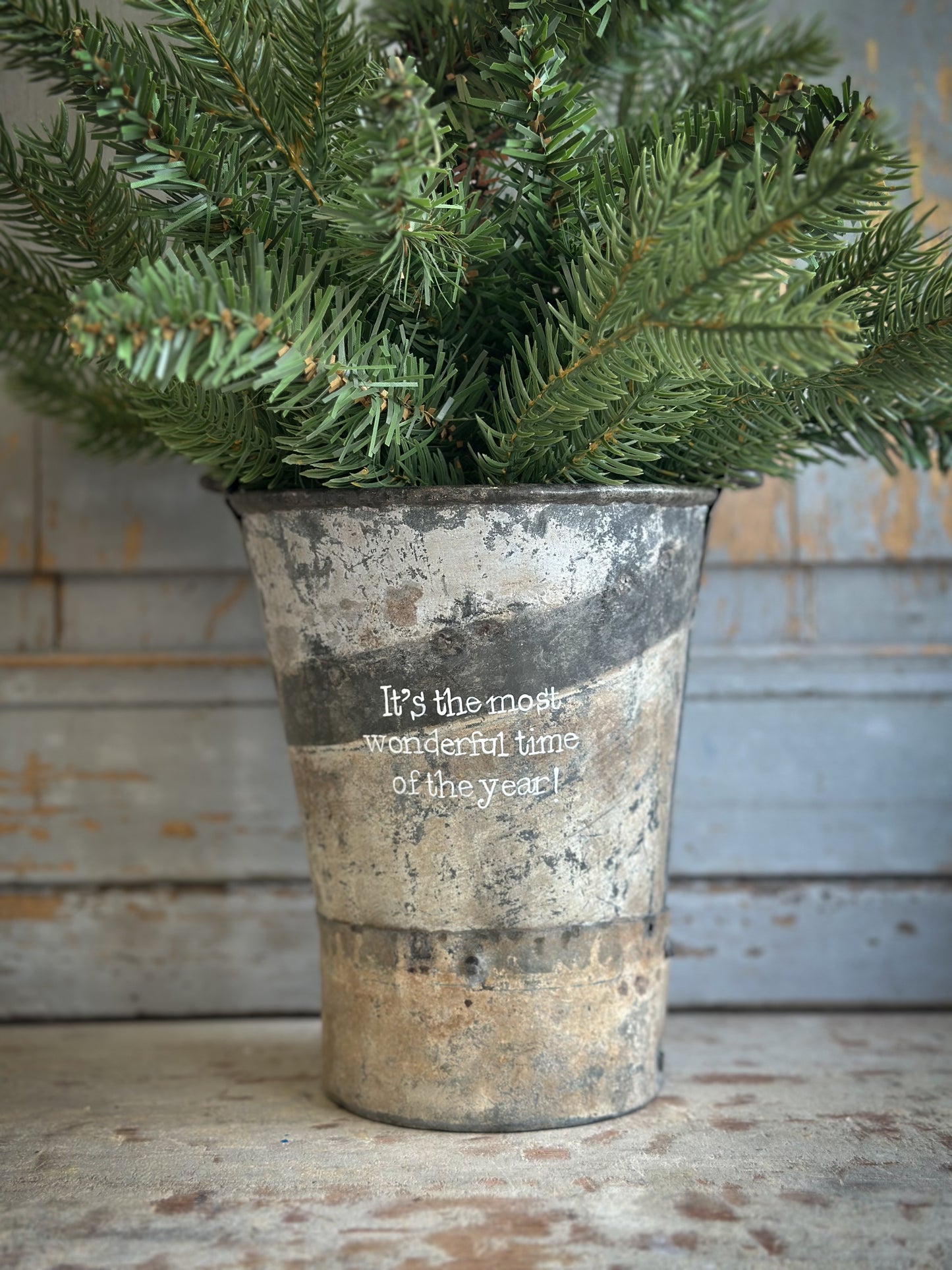A Recycled Metal Mini Christmas Tree Bucket With A Hand Painted Quote