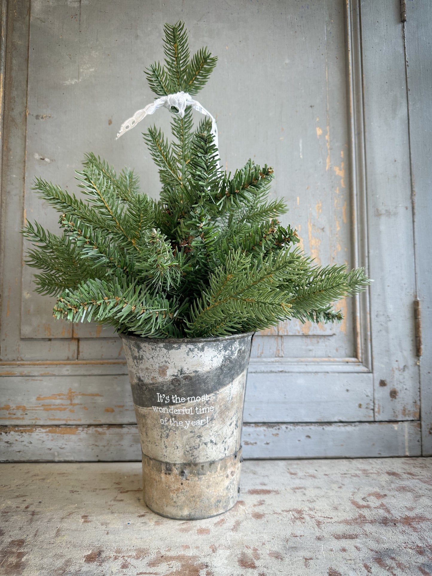 A Recycled Metal Mini Christmas Tree Bucket With A Hand Painted Quote