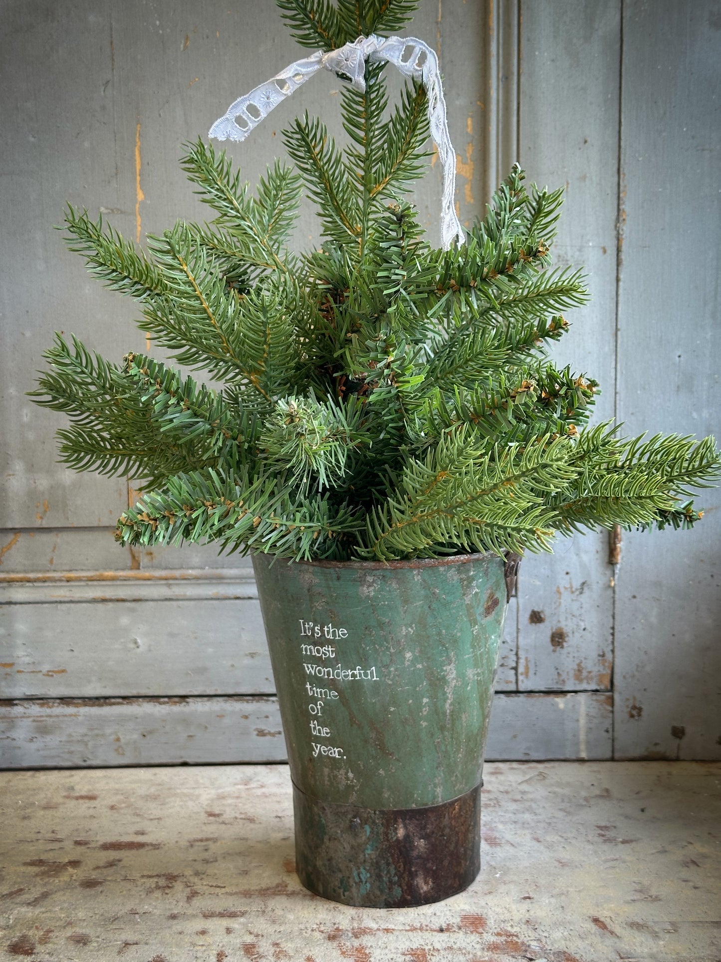 A Recycled Metal Mini Christmas Tree Bucket With A Hand Painted Quote