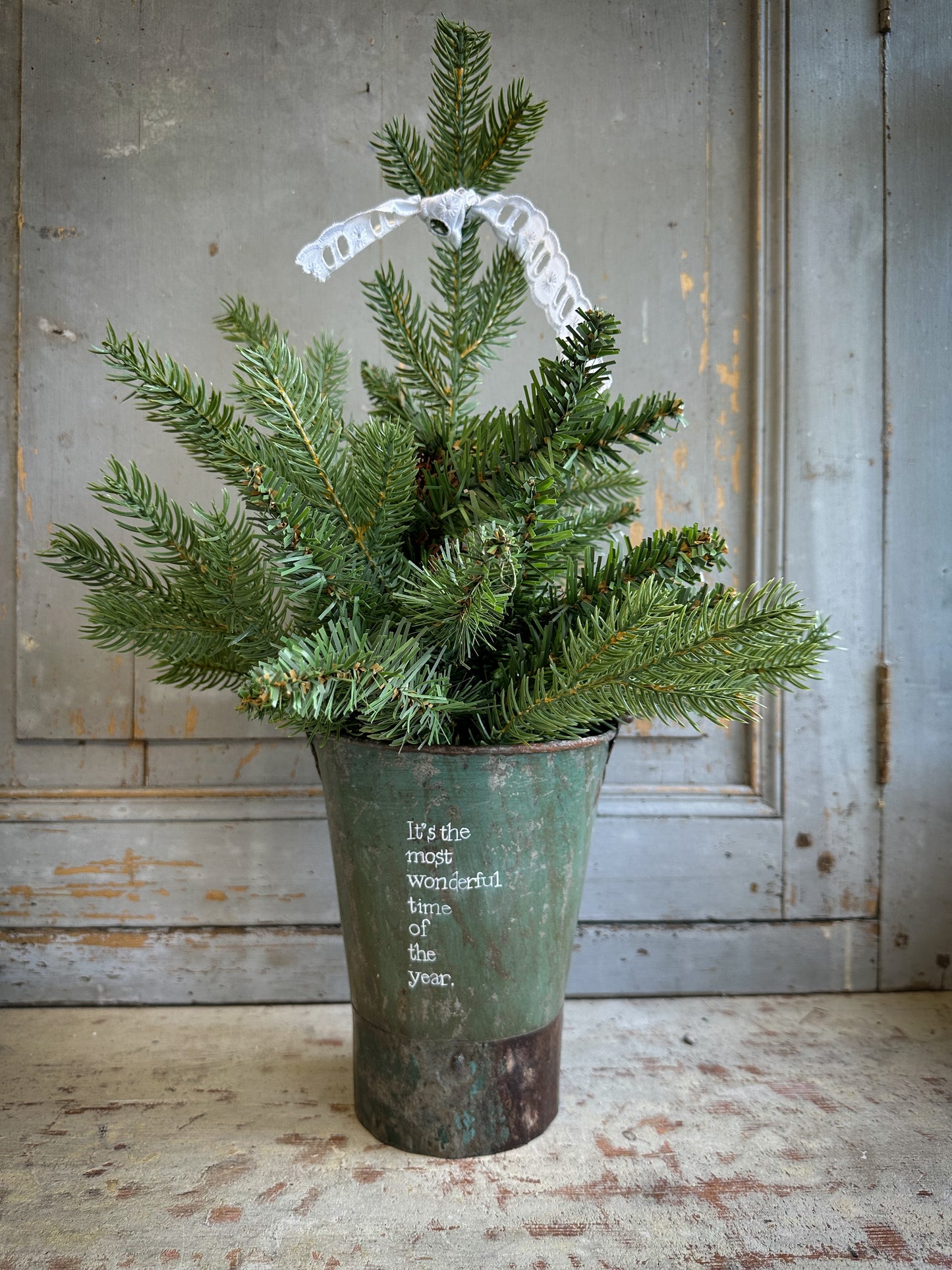 A Recycled Metal Mini Christmas Tree Bucket With A Hand Painted Quote