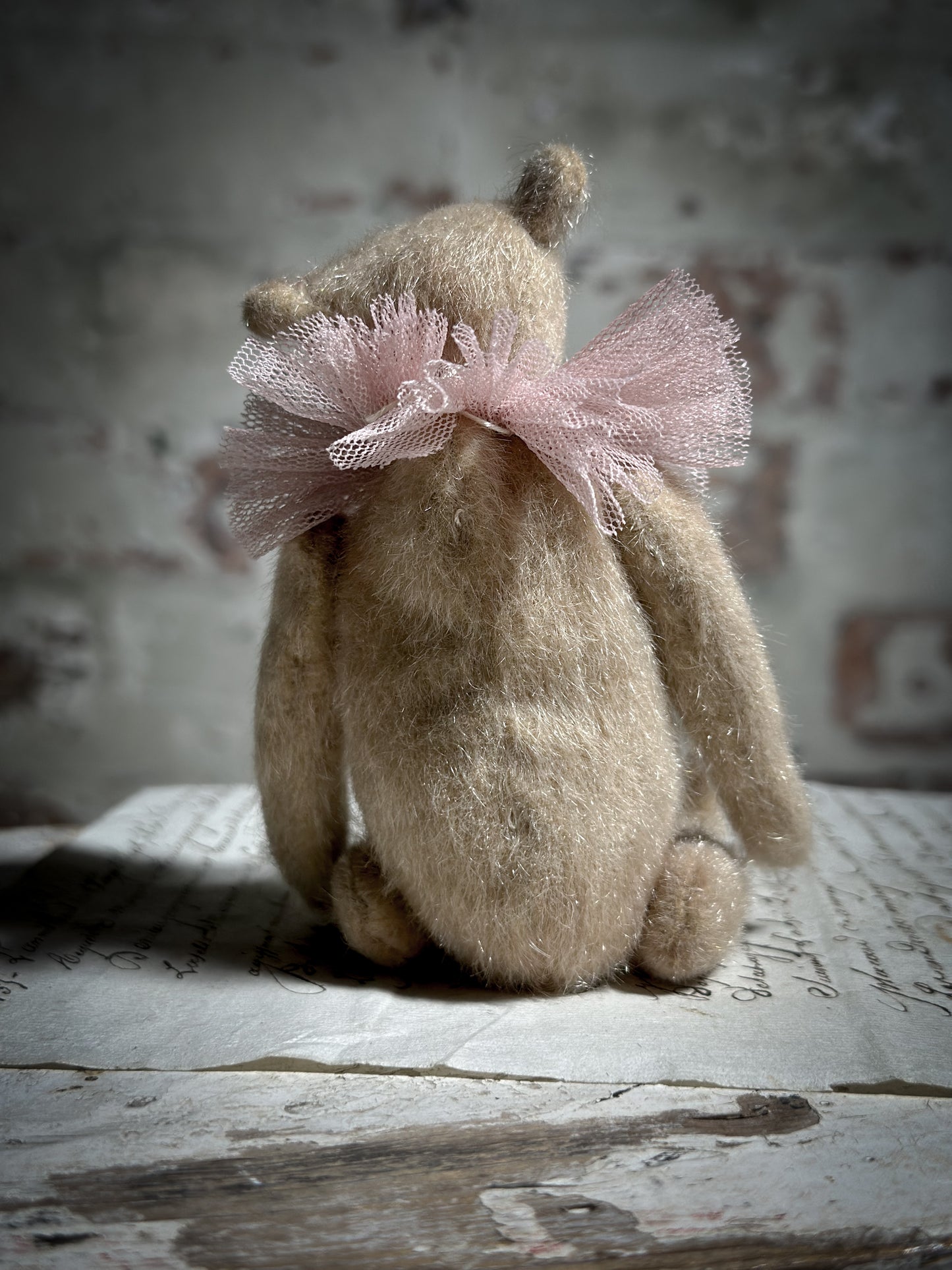 A beautiful hand made jointed collector’s teddy bear with antique pink tulle ruffle