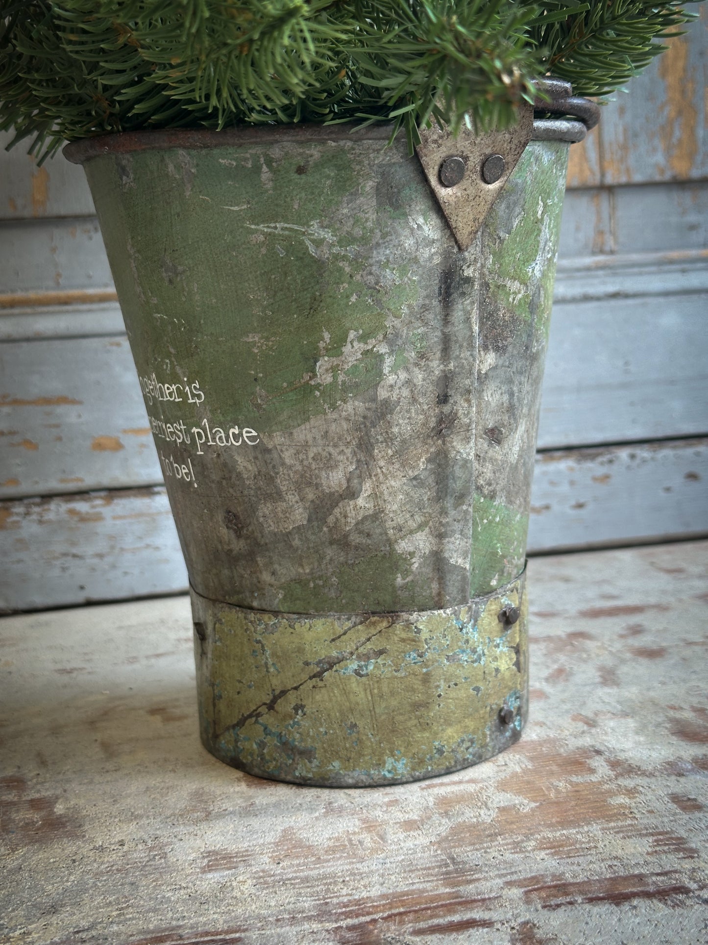 A Recycled Metal Mini Christmas Tree Bucket With A Hand Painted Quote