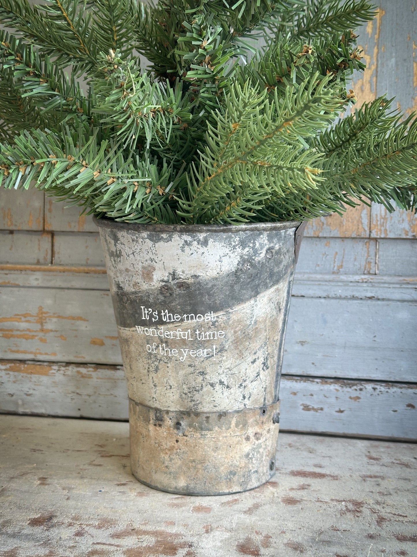 A Recycled Metal Mini Christmas Tree Bucket With A Hand Painted Quote