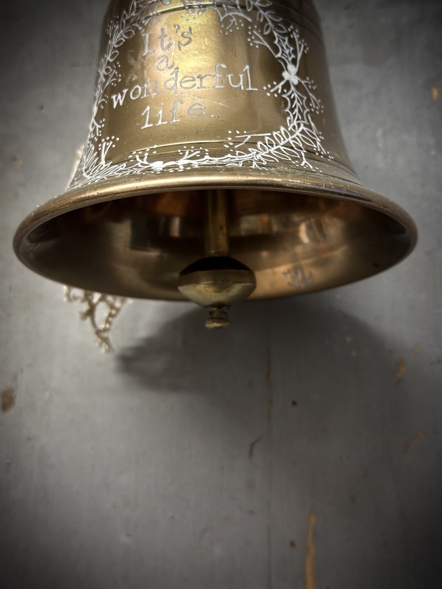 A vintage brass hand held bell with a hand painted quote