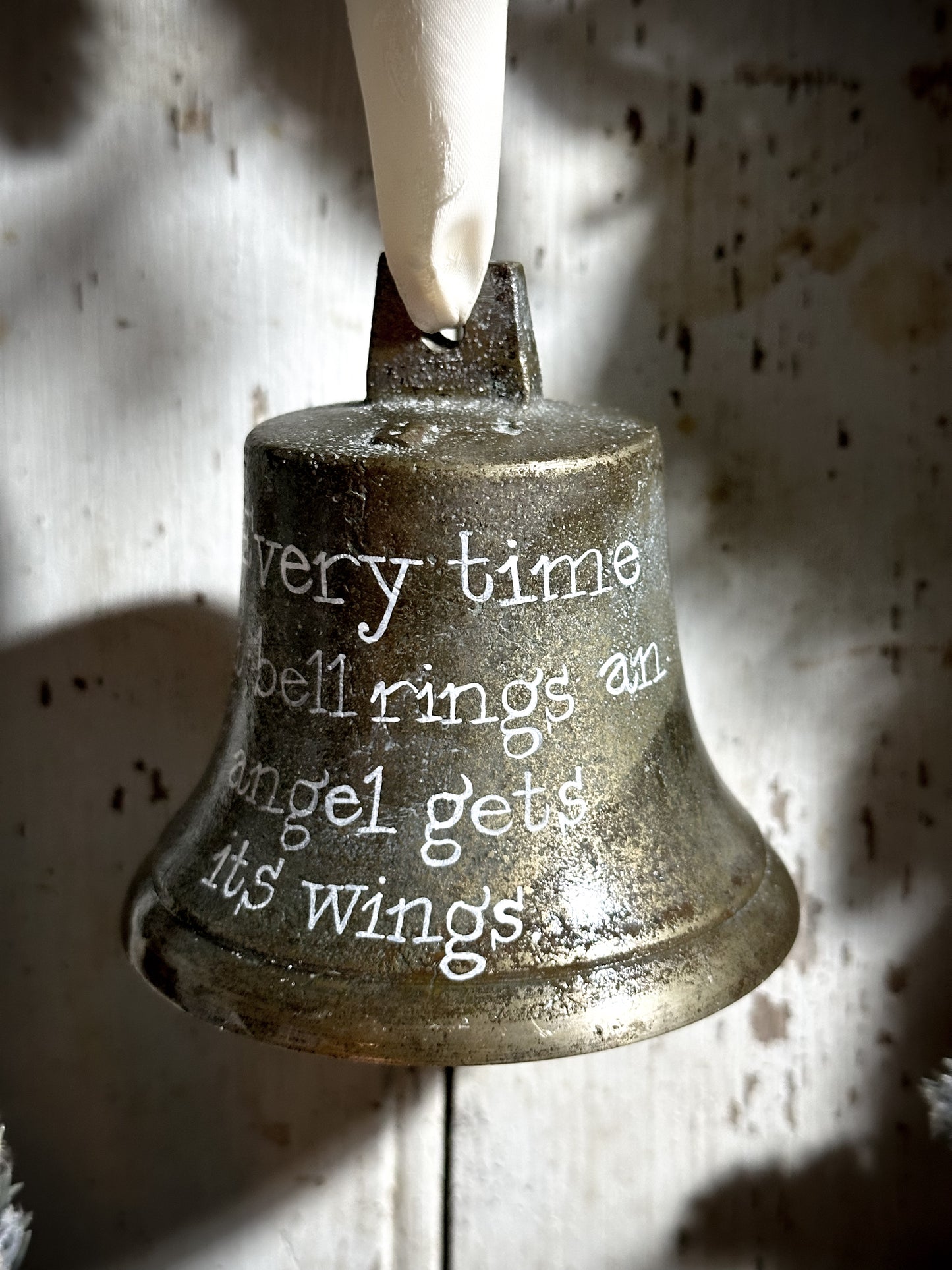 A vintage brass bell with a hand painted quote