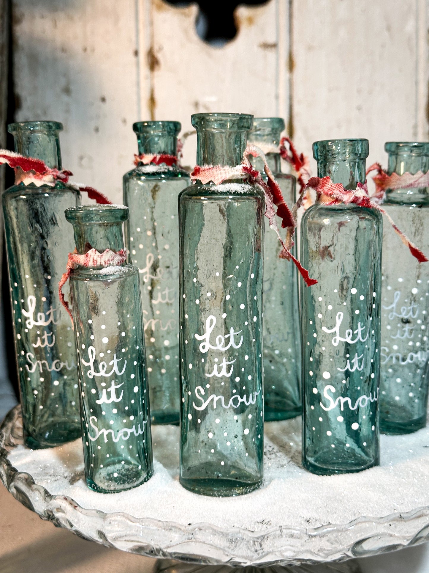 A beautiful Victorian cylinder bottle painted with a Christmas quote “Let it Snow”