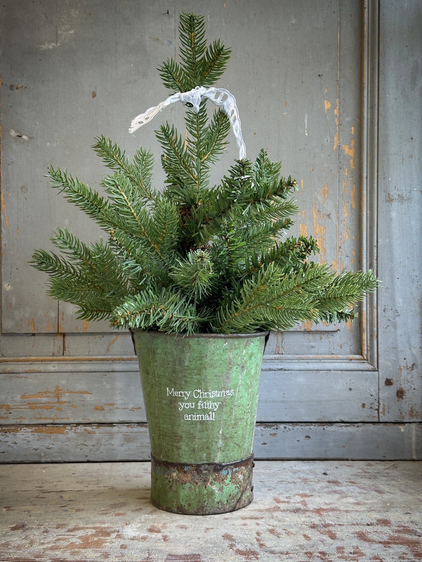 A Recycled Metal Mini Christmas Tree Bucket With A Hand Painted Quote