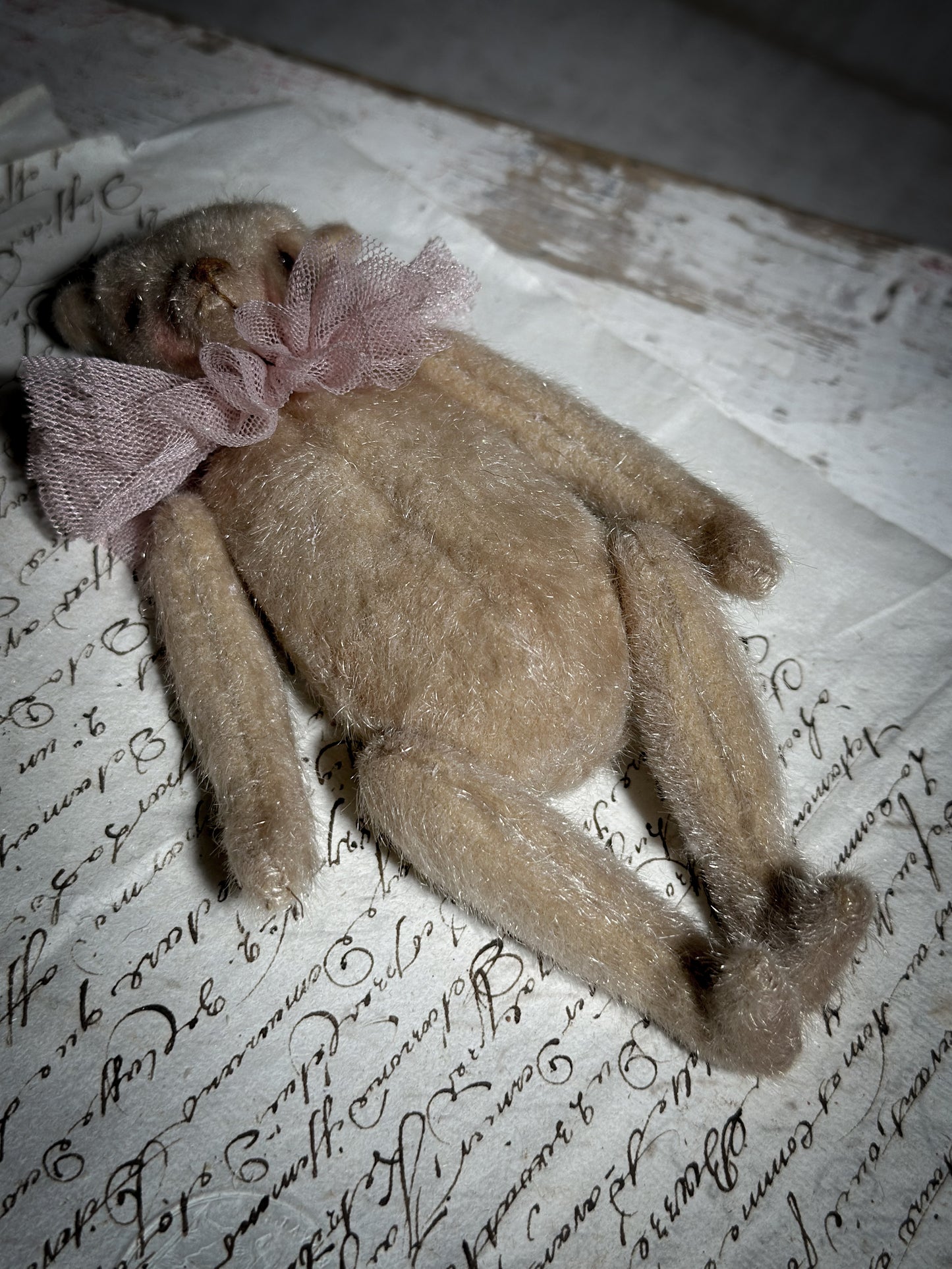 A beautiful hand made jointed collector’s teddy bear with antique pink tulle ruffle