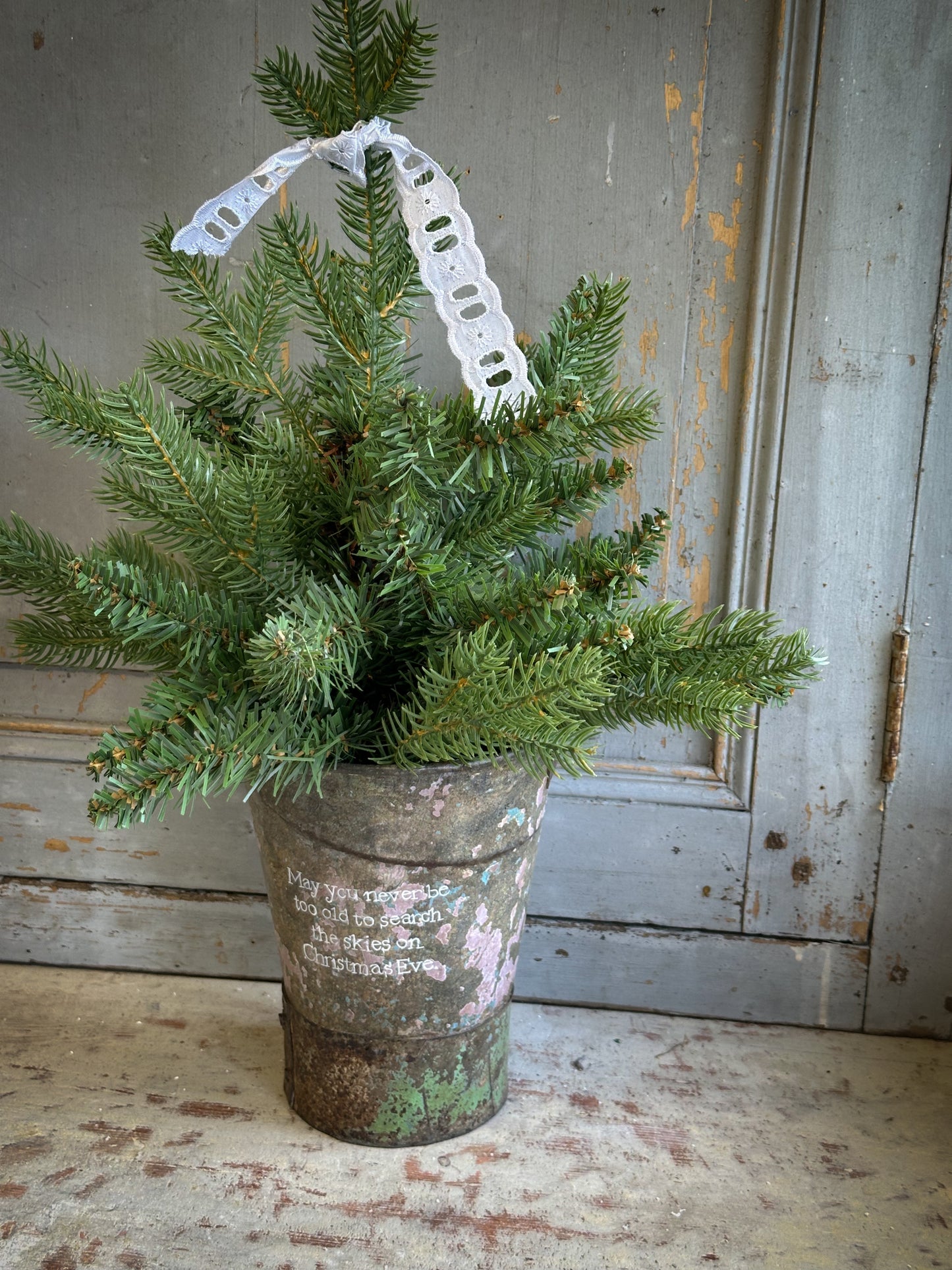 A Recycled Metal Mini Christmas Tree Bucket With A Hand Painted Quote