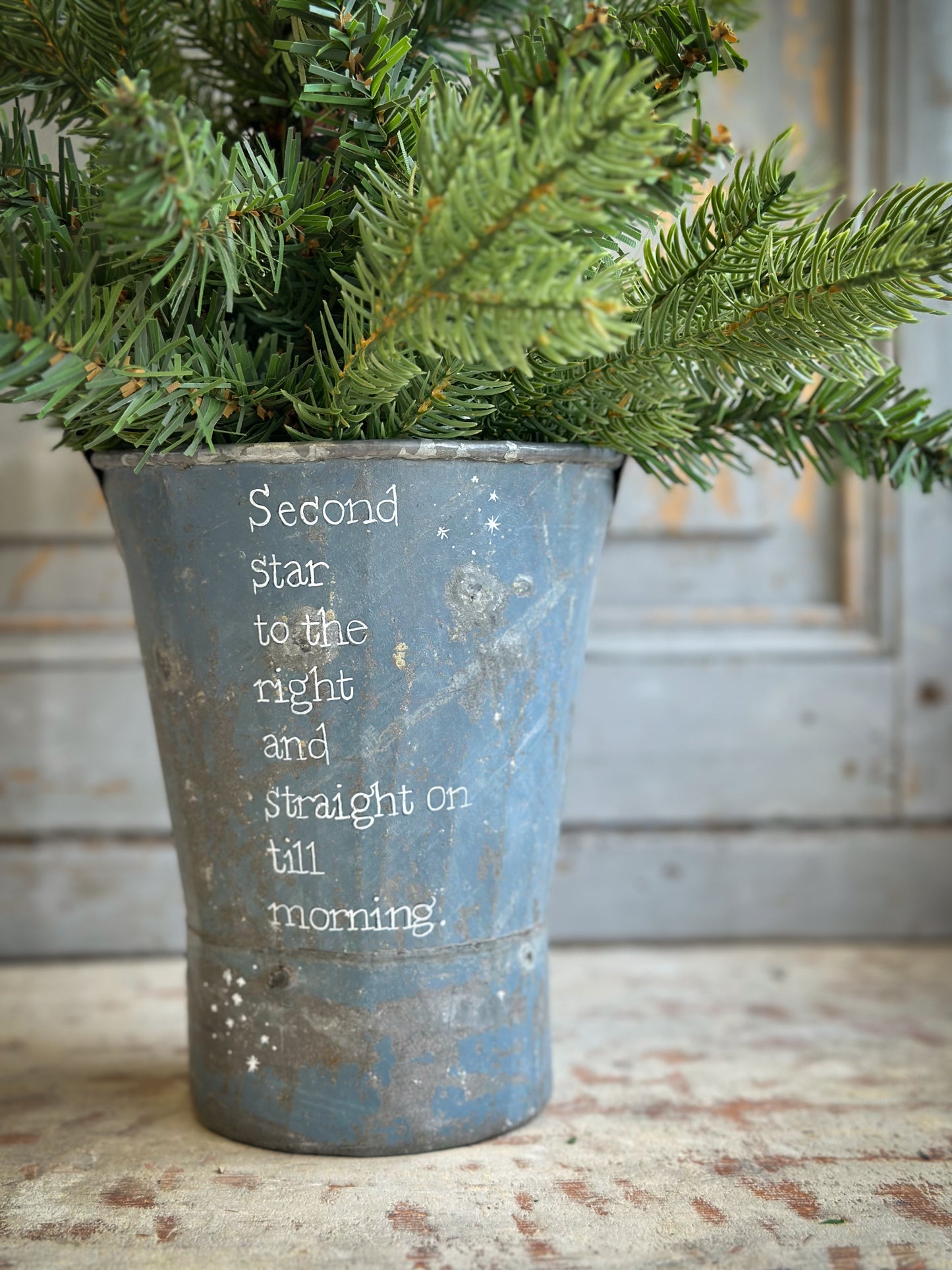 A Recycled Metal Mini Christmas Tree Bucket With A Hand Painted Quote