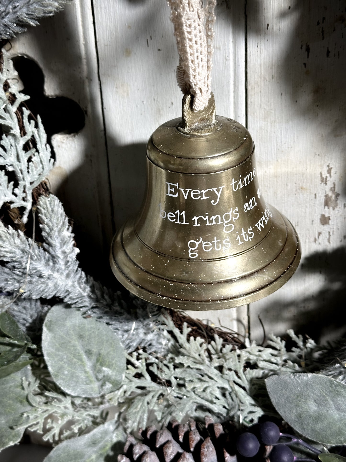 A vintage brass bell with a hand painted quote