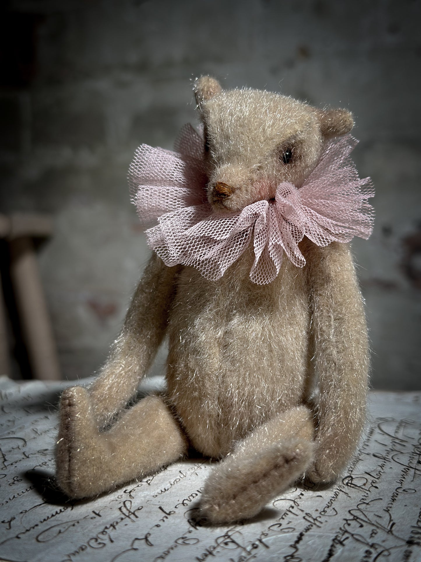 A beautiful hand made jointed collector’s teddy bear with antique pink tulle ruffle