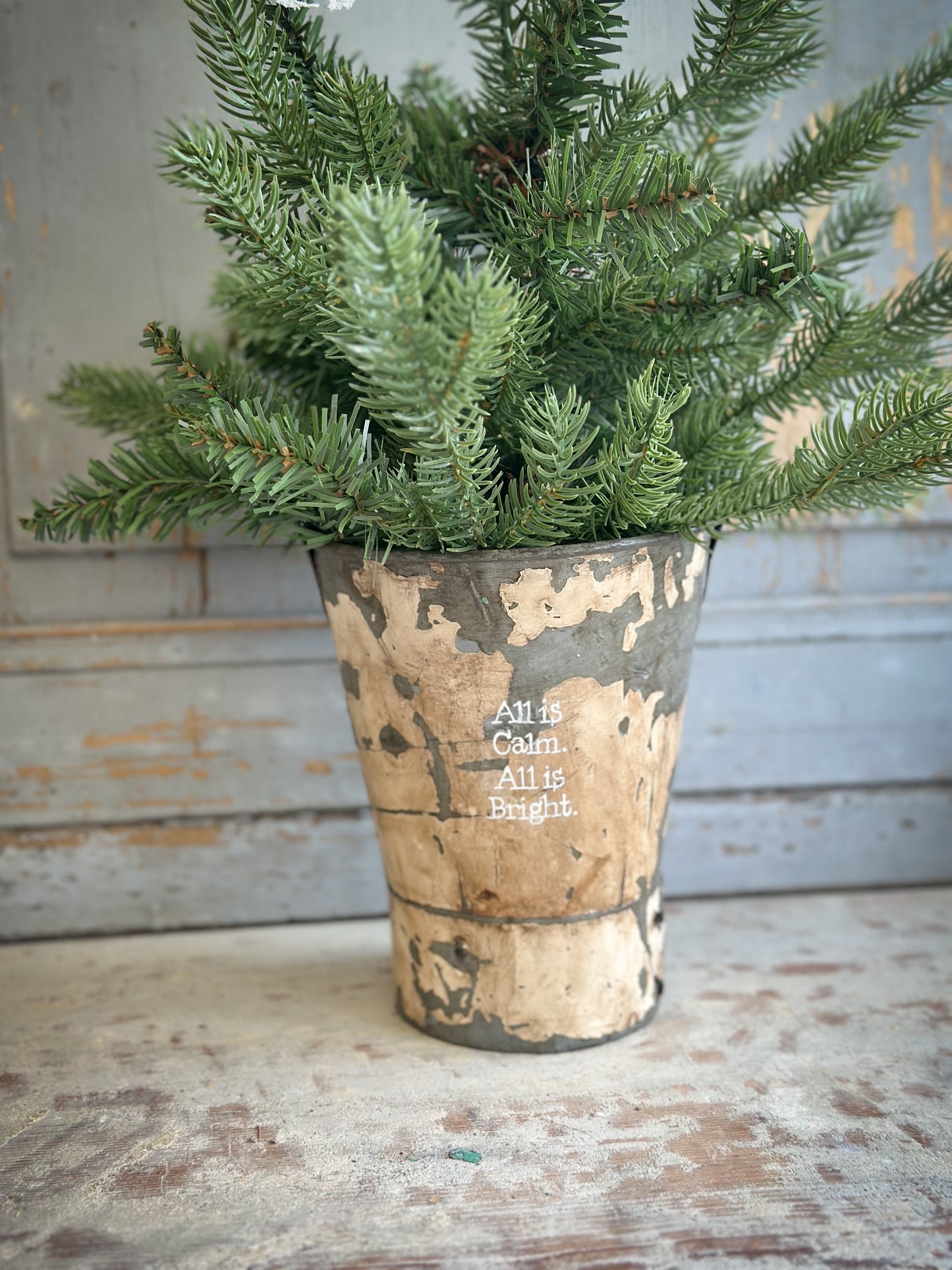 A Recycled Metal Mini Christmas Tree Bucket With A Hand Painted Quote