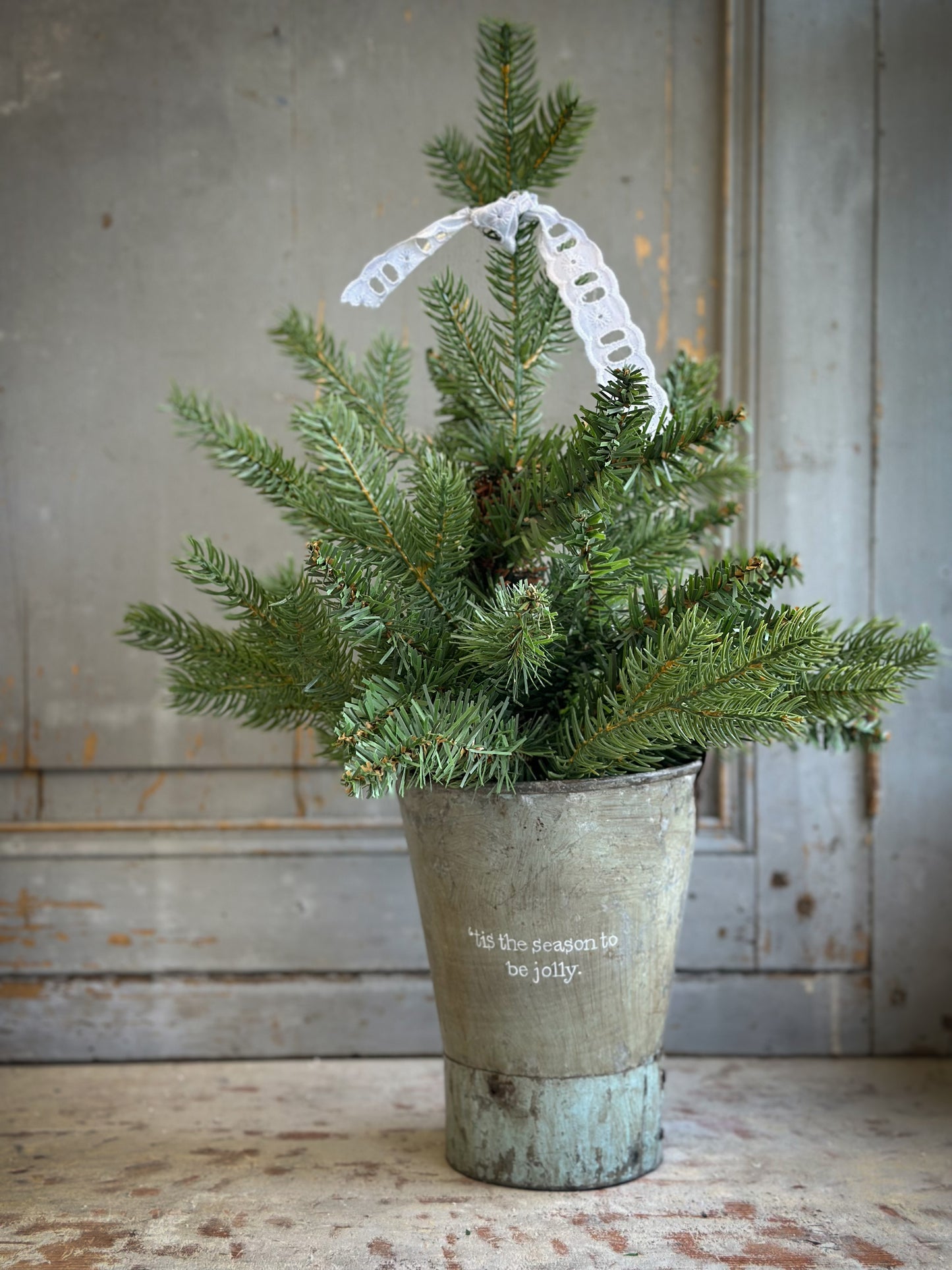 A Recycled Metal Mini Christmas Tree Bucket With A Hand Painted Quote