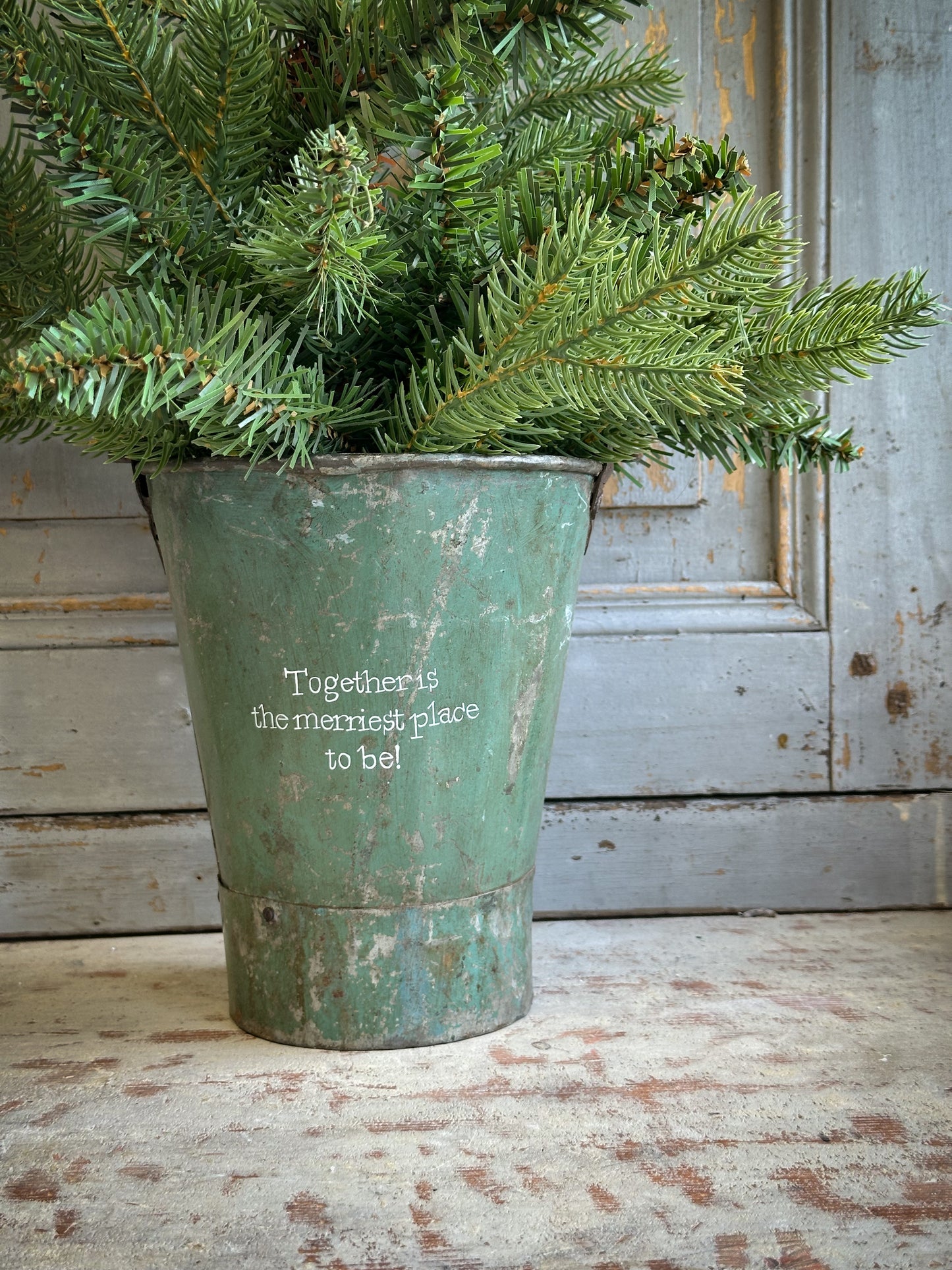 A Recycled Metal Mini Christmas Tree Bucket With A Hand Painted Quote