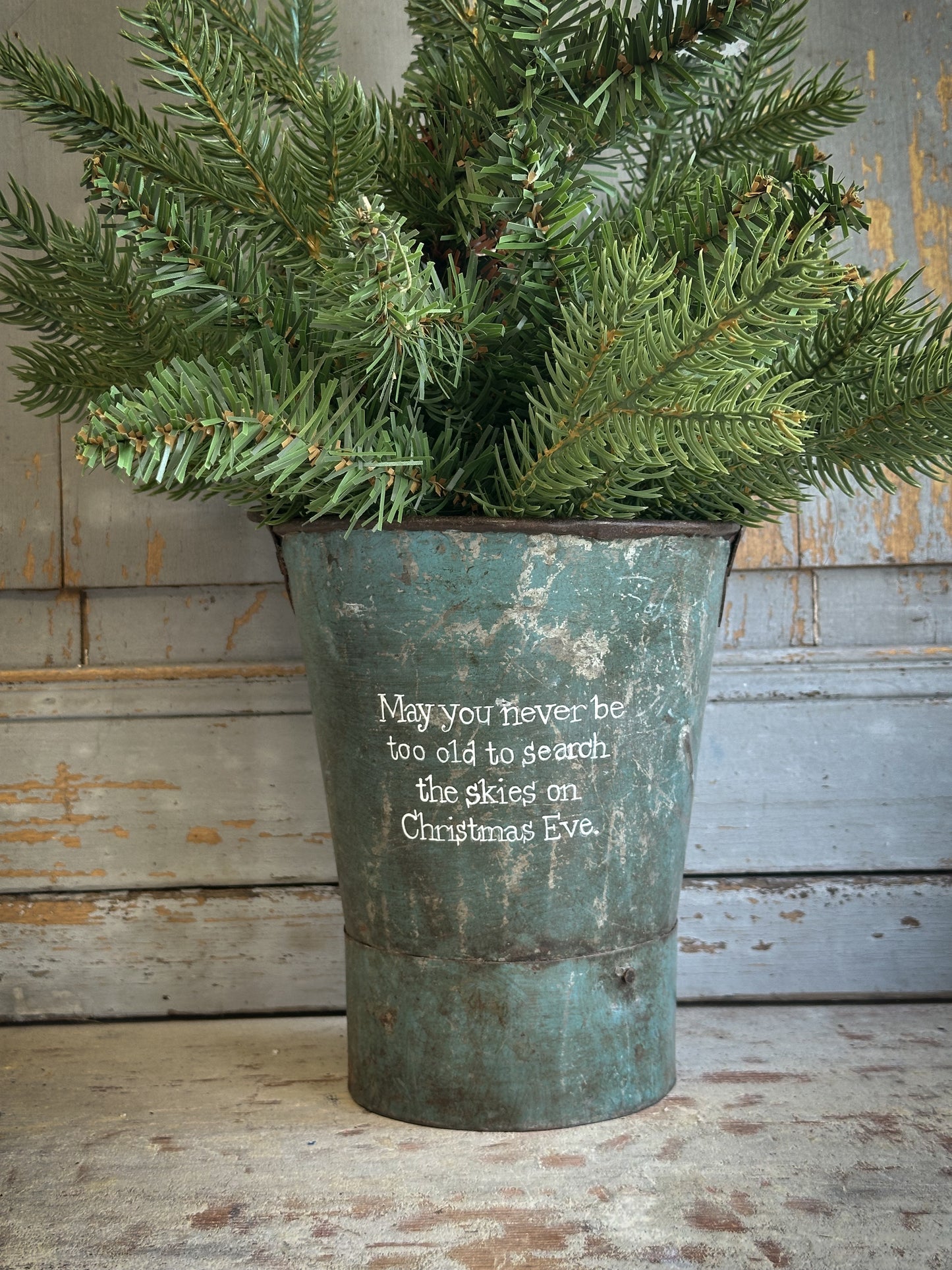 A Recycled Metal Mini Christmas Tree Bucket With A Hand Painted Quote