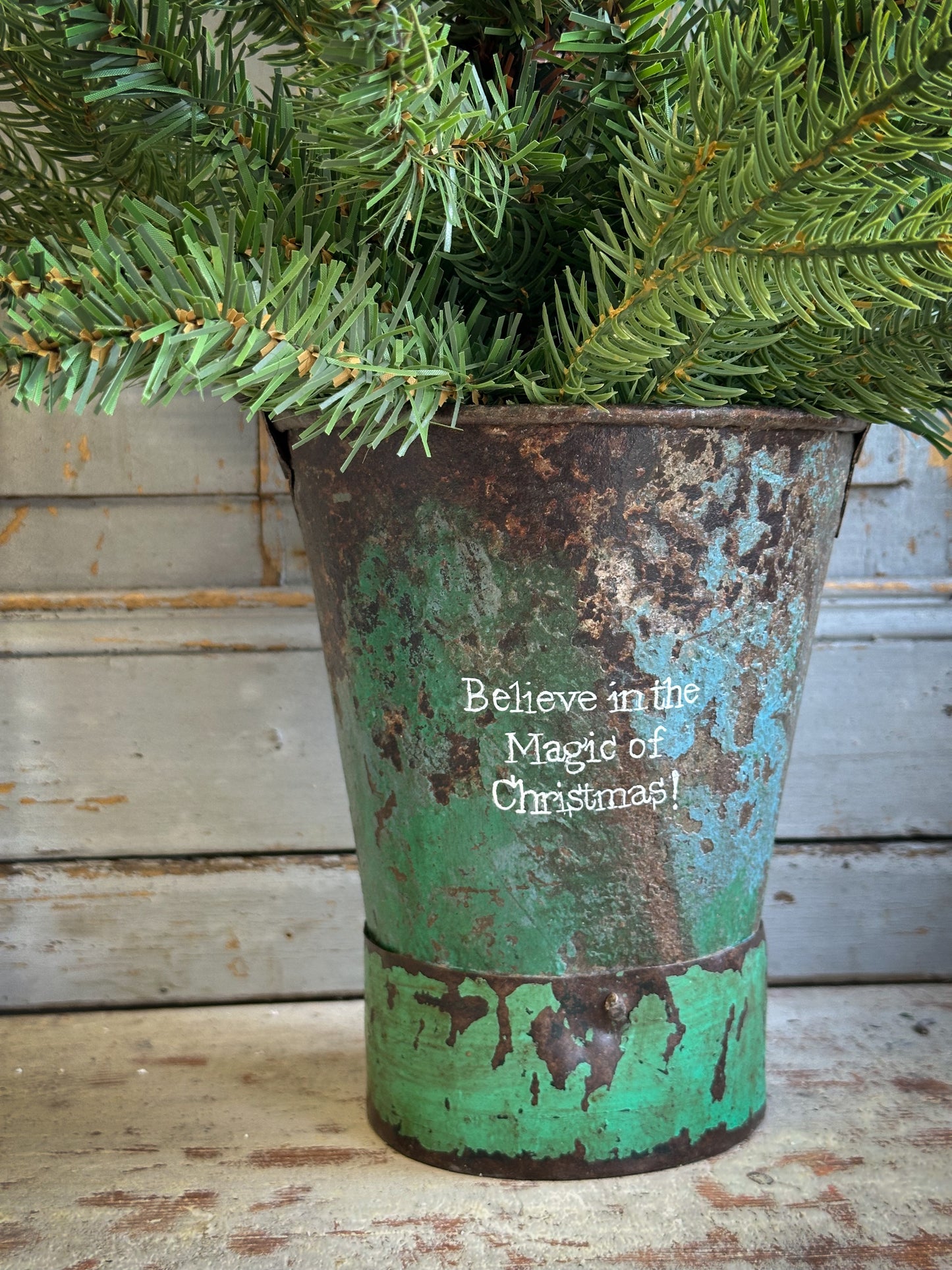 A Recycled Metal Mini Christmas Tree Bucket With A Hand Painted Quote