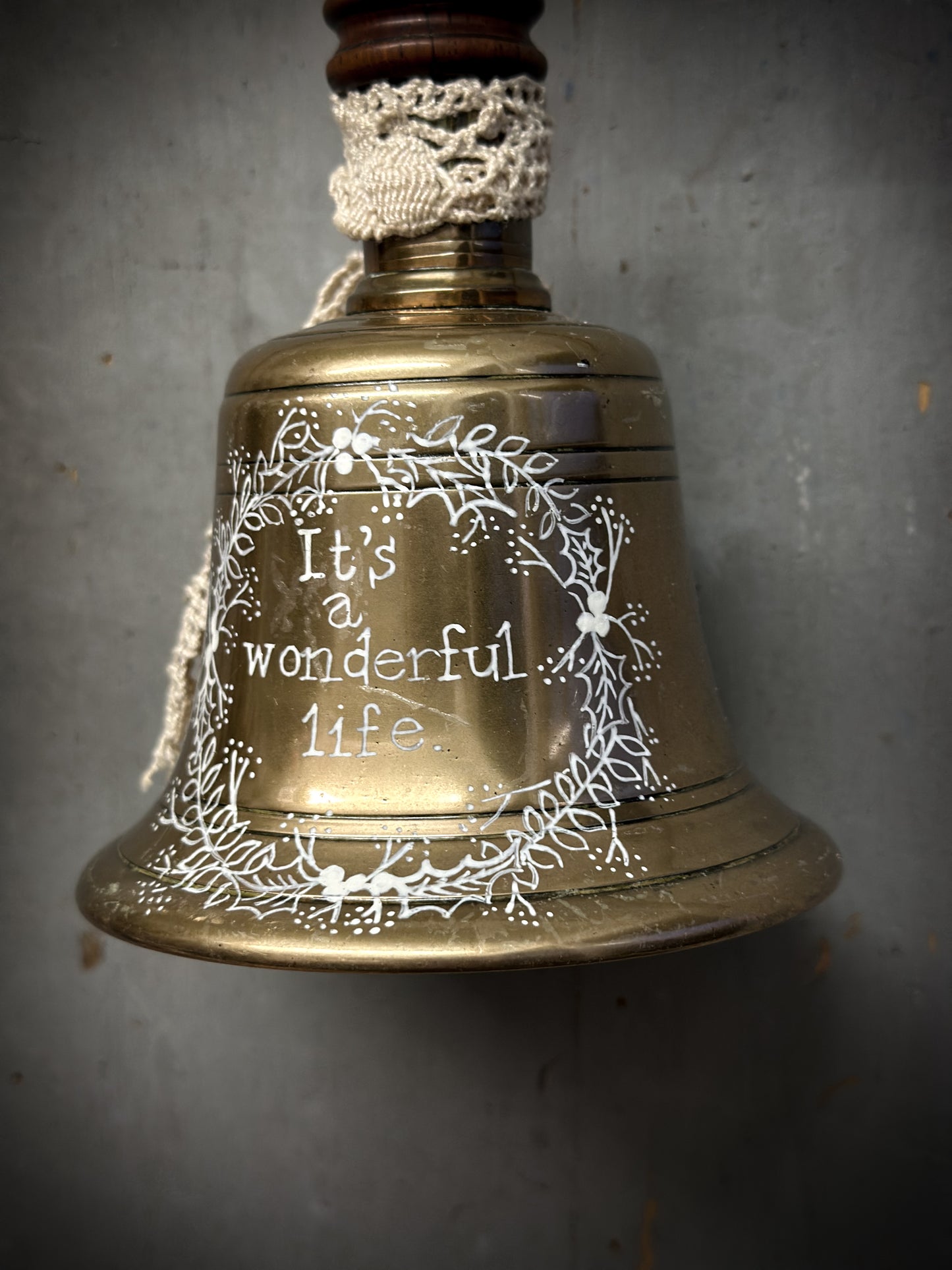 A vintage brass hand held bell with a hand painted quote
