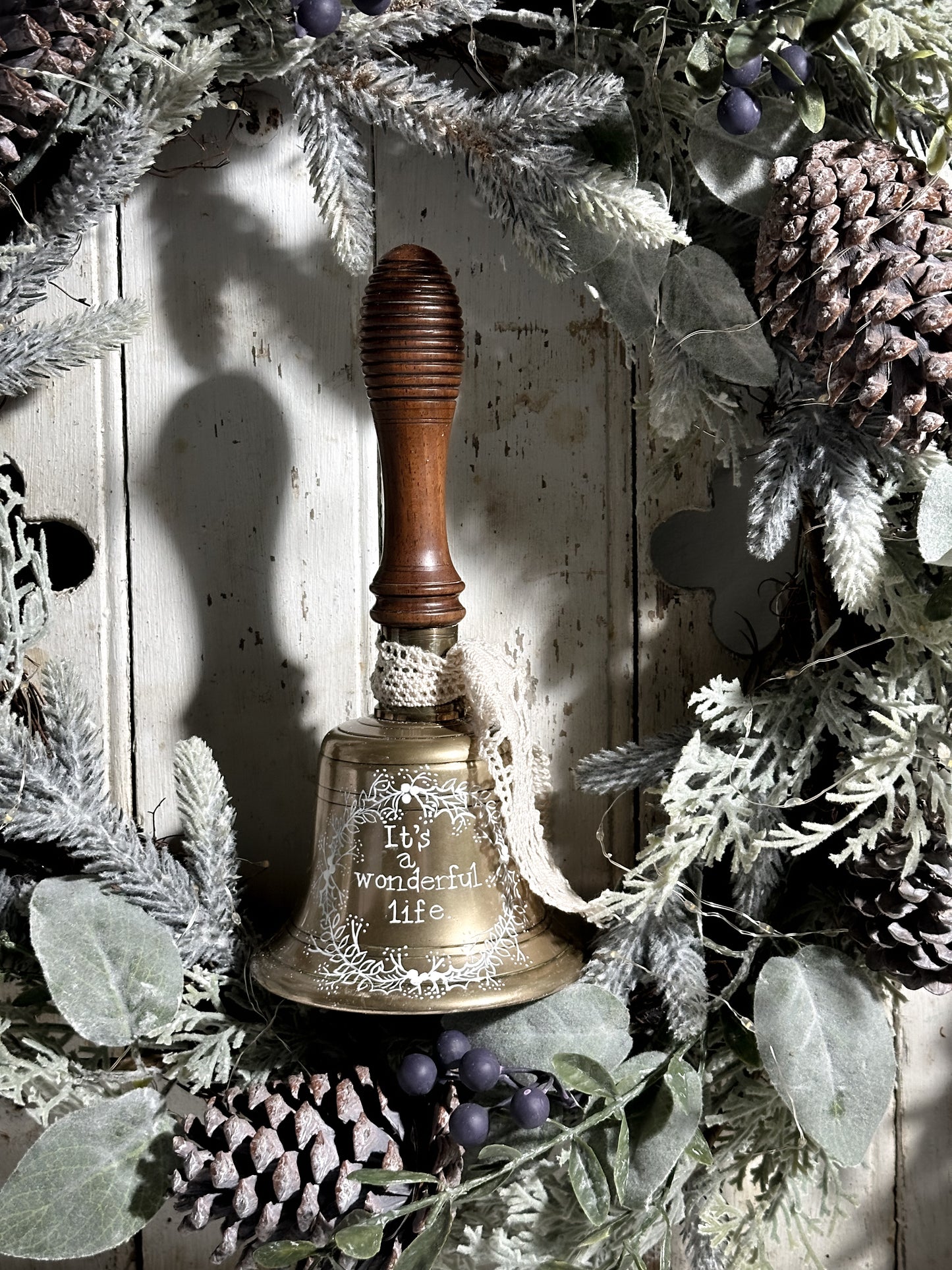 A vintage brass hand held bell with a hand painted quote