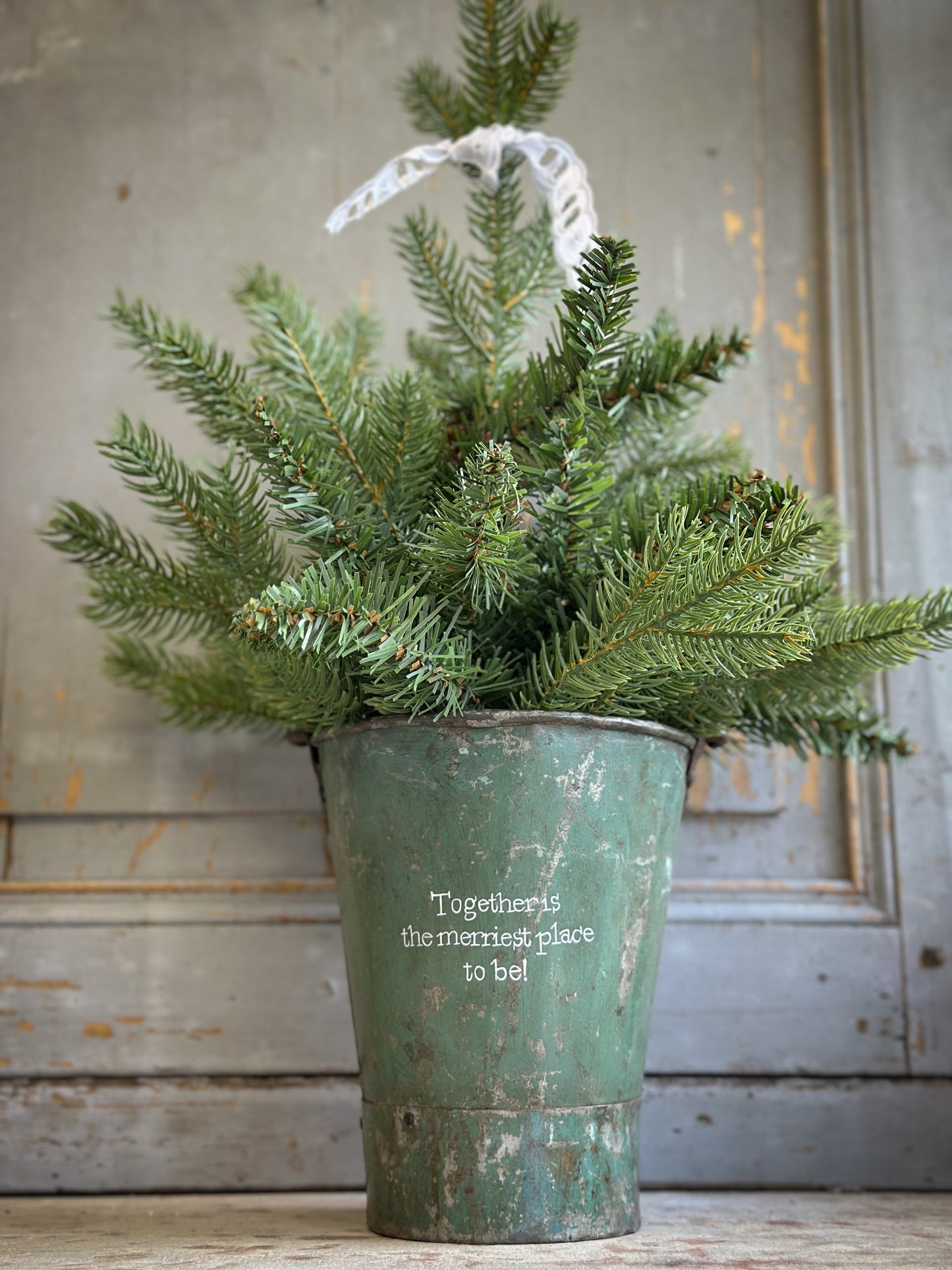 A Recycled Metal Mini Christmas Tree Bucket With A Hand Painted Quote