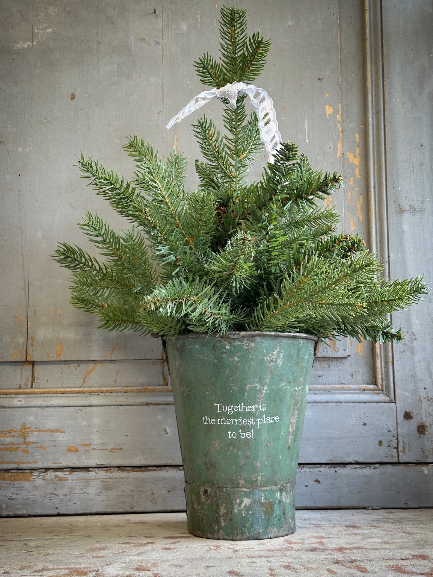 A Recycled Metal Mini Christmas Tree Bucket With A Hand Painted Quote