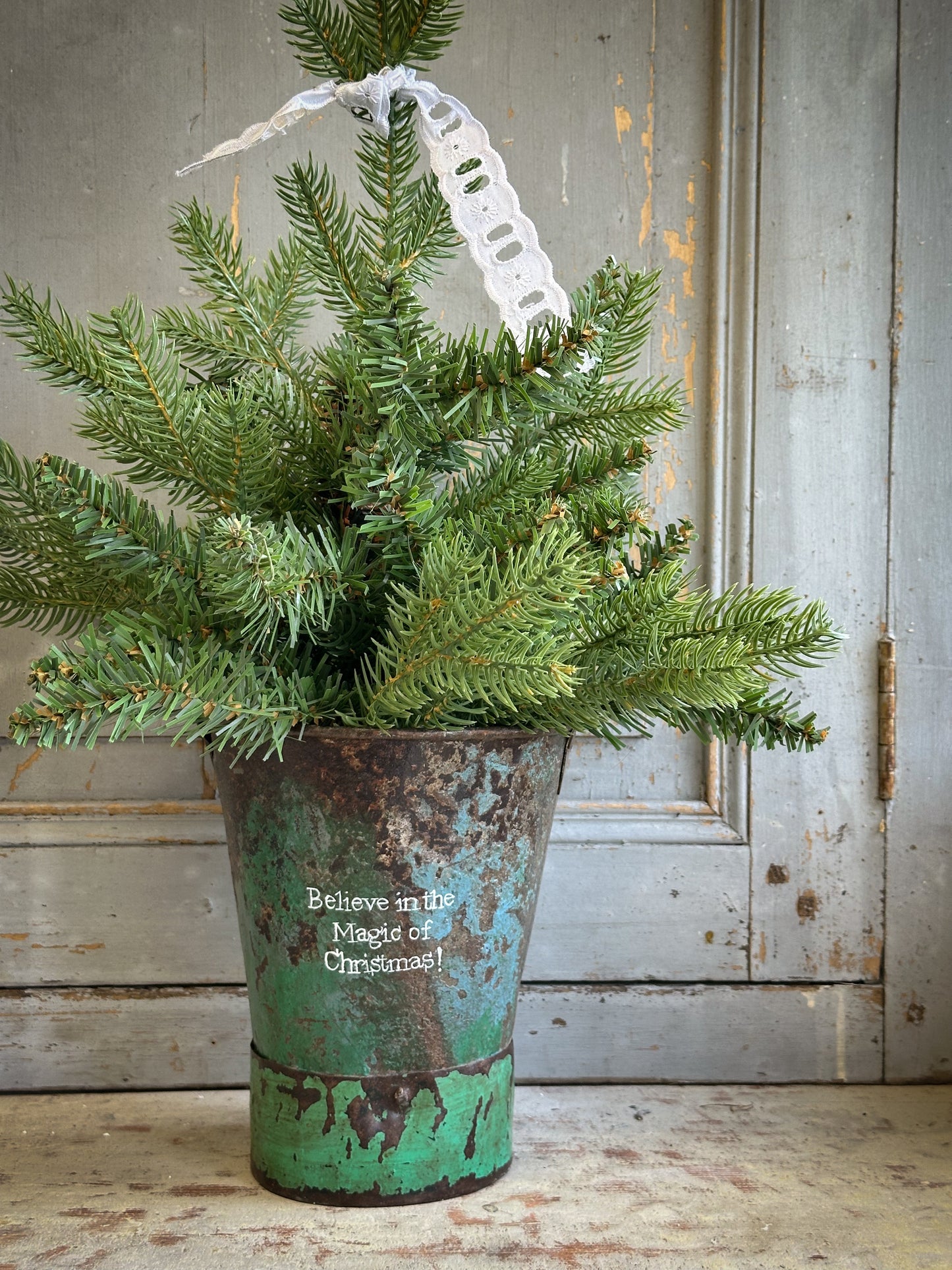 A Recycled Metal Mini Christmas Tree Bucket With A Hand Painted Quote