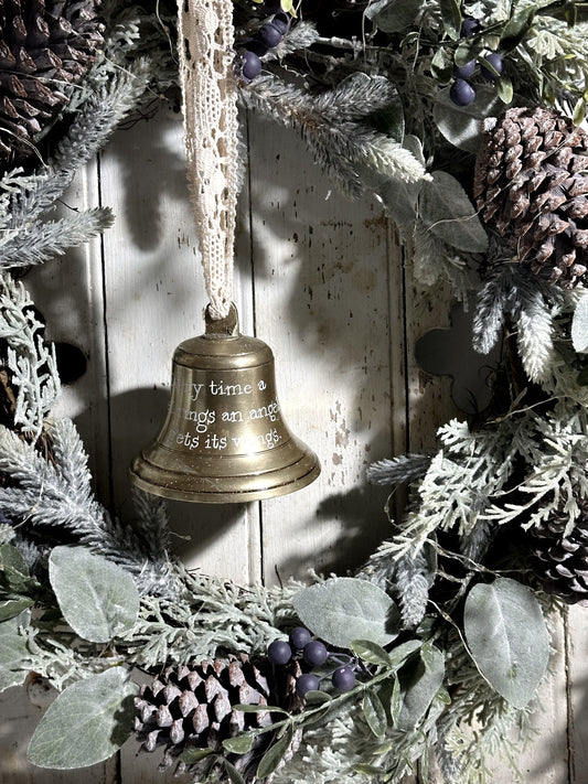 A vintage brass bell with a hand painted quote