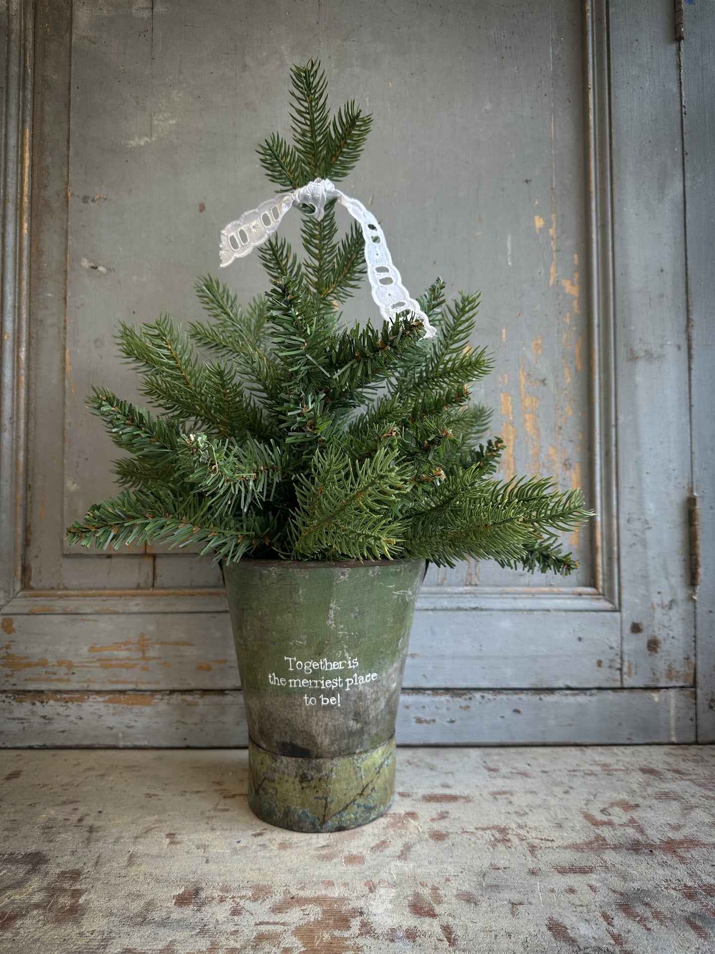 A Recycled Metal Mini Christmas Tree Bucket With A Hand Painted Quote