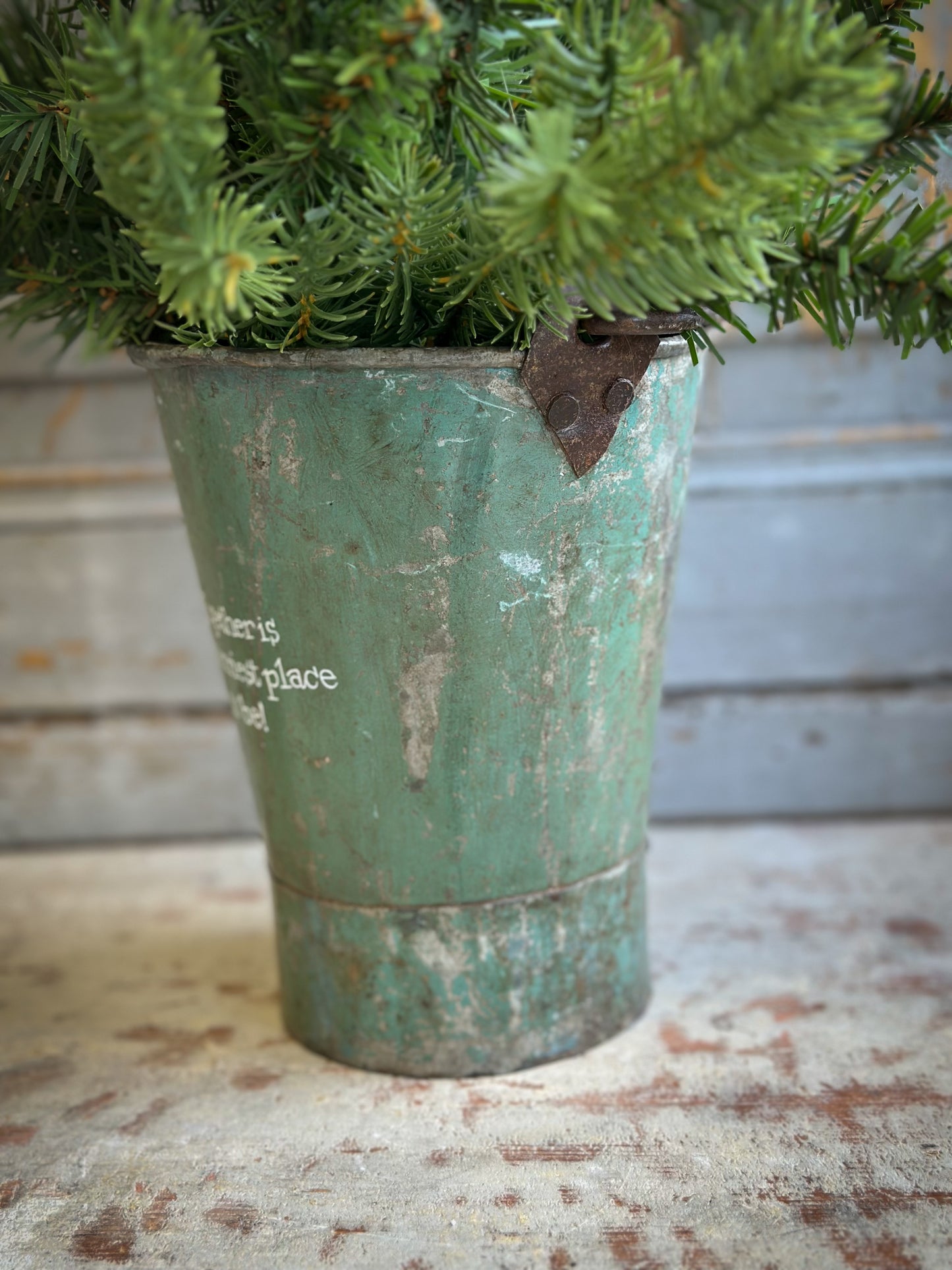 A Recycled Metal Mini Christmas Tree Bucket With A Hand Painted Quote