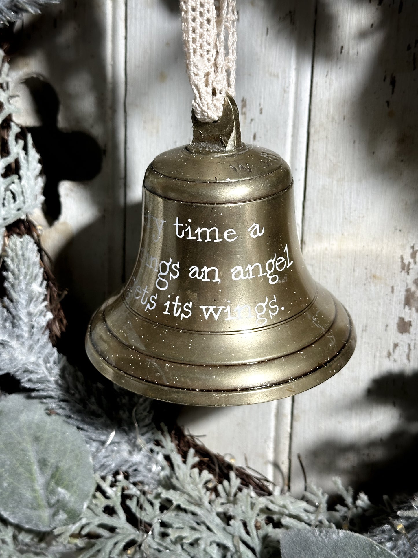 A vintage brass bell with a hand painted quote