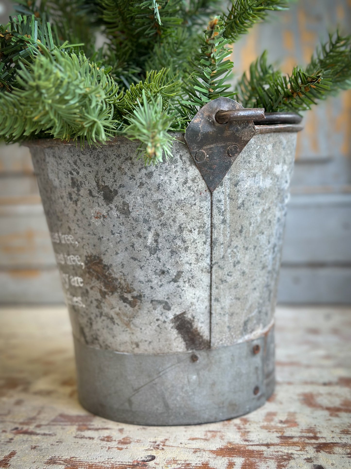 A Recycled Metal Small Christmas Tree Bucket With A Hand Painted Quote