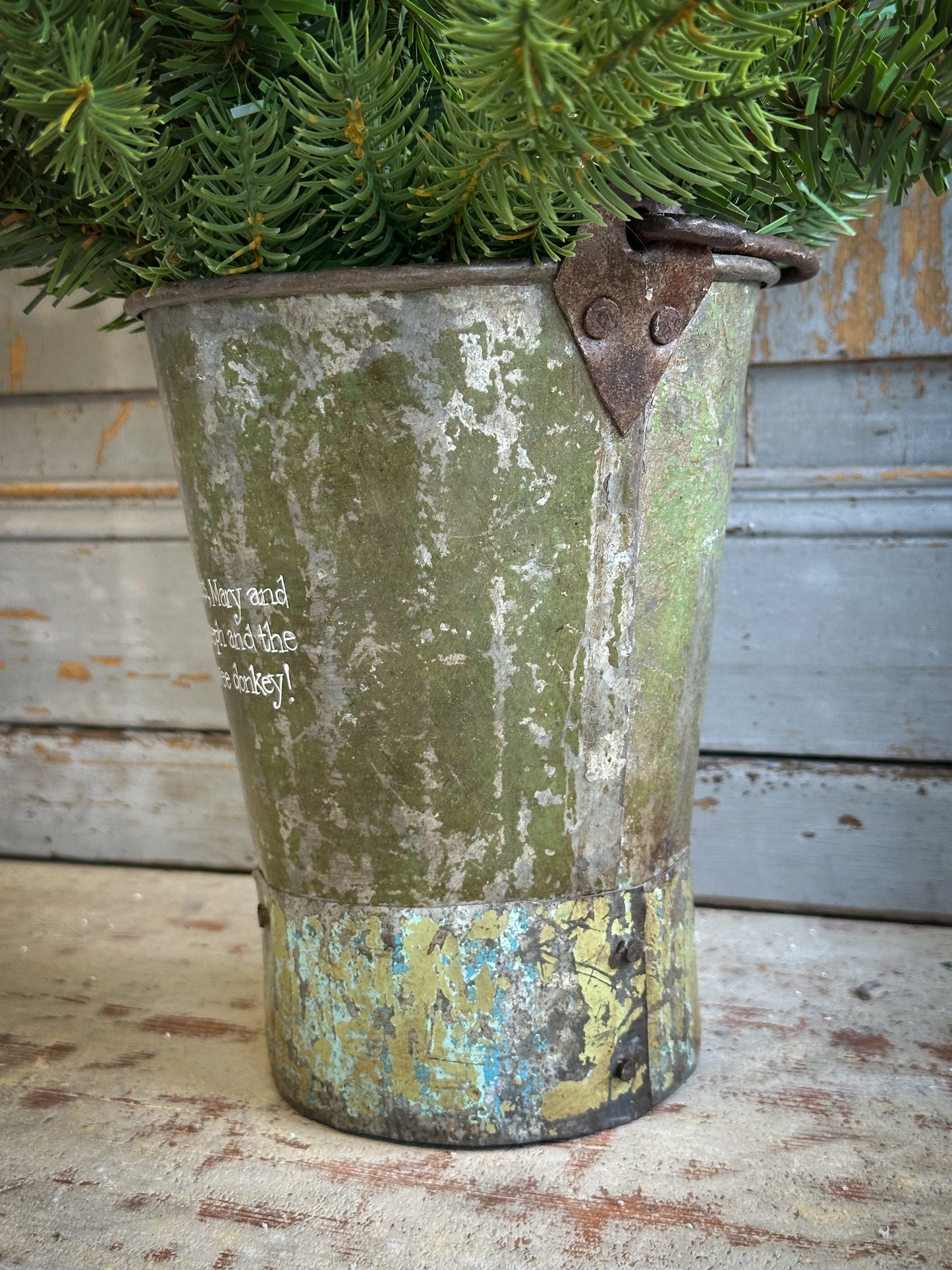 A Recycled Metal Mini Christmas Tree Bucket With A Hand Painted Quote