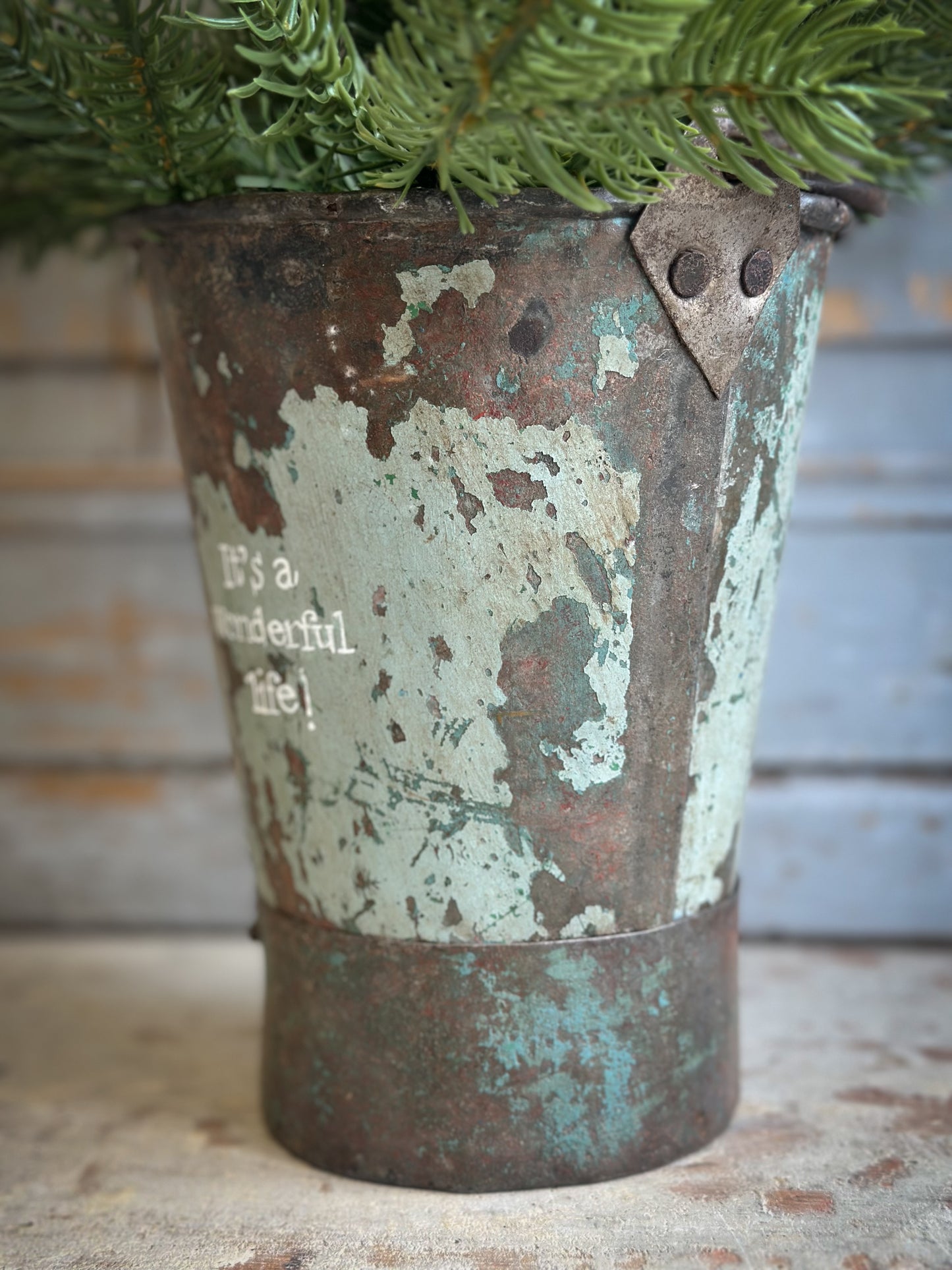 A Recycled Metal Mini Christmas Tree Bucket With A Hand Painted Quote