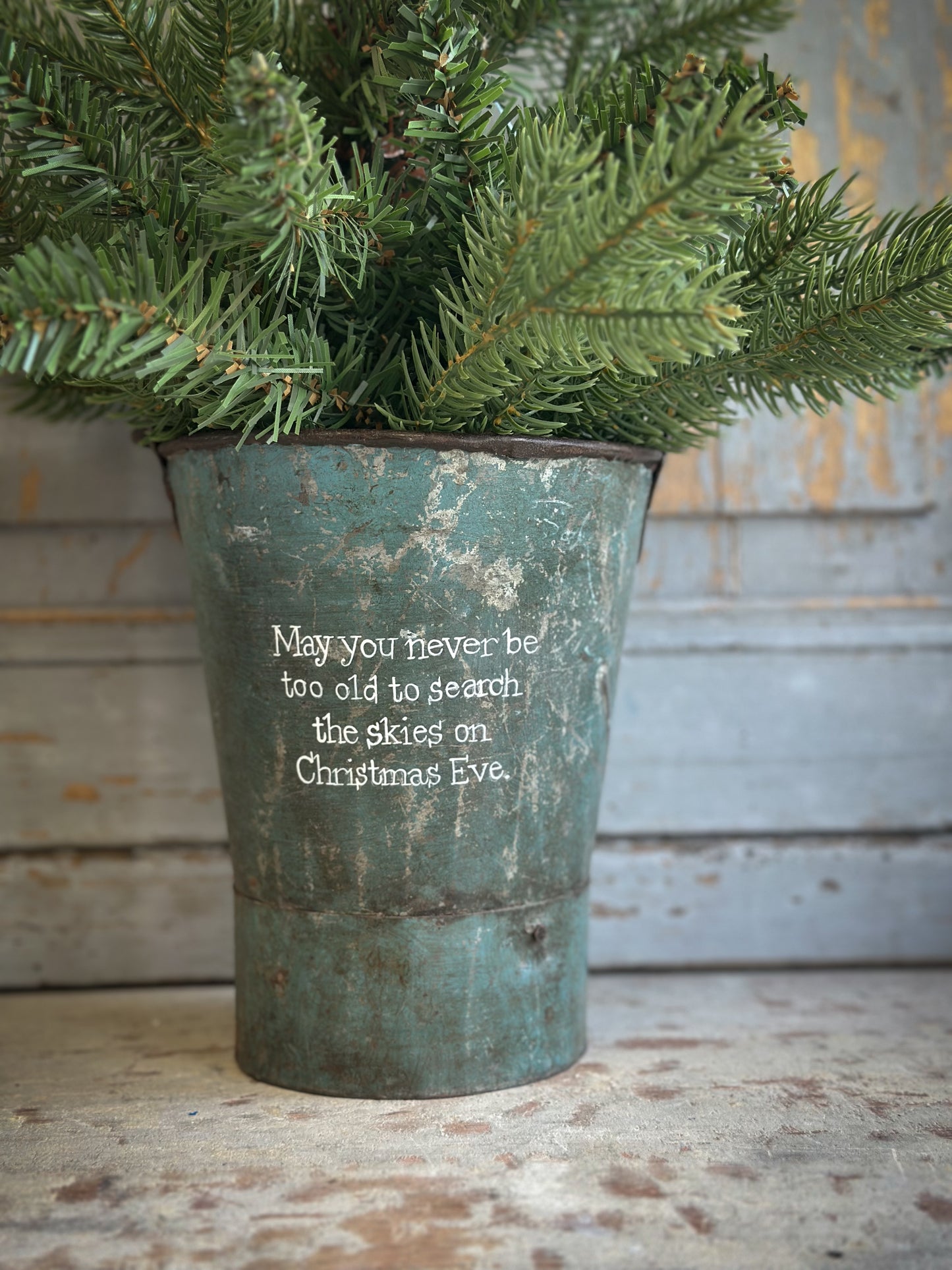 A Recycled Metal Mini Christmas Tree Bucket With A Hand Painted Quote