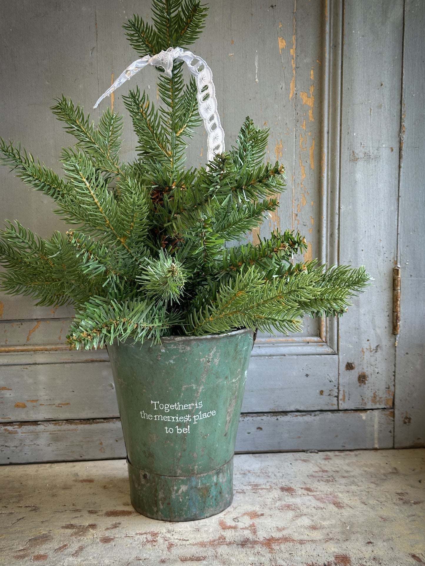 A Recycled Metal Mini Christmas Tree Bucket With A Hand Painted Quote