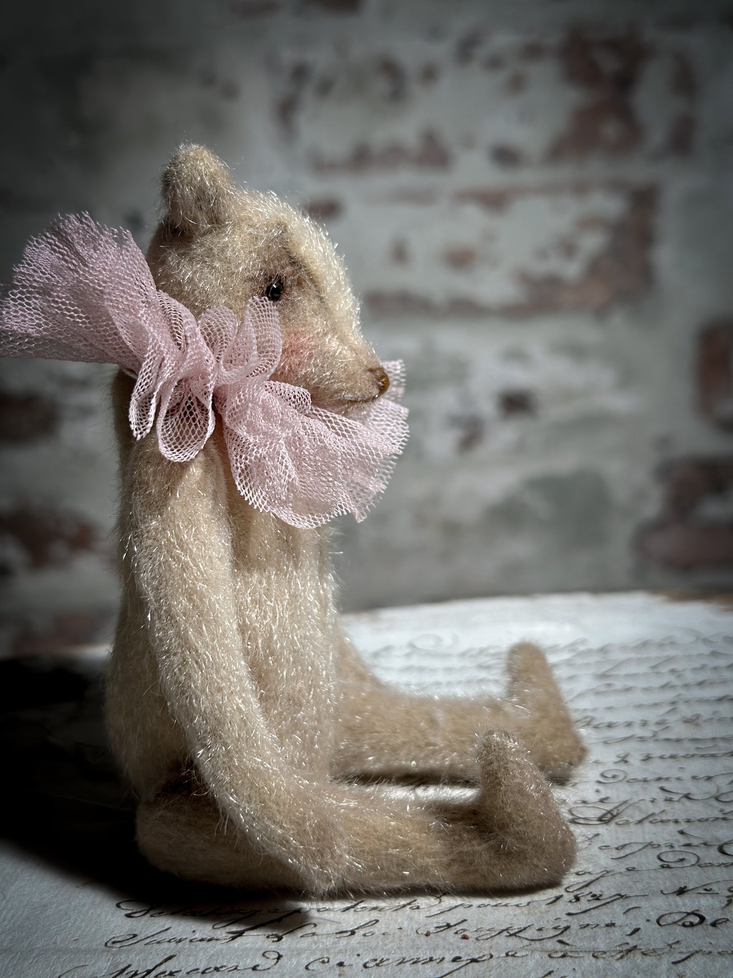 A beautiful hand made jointed collector’s teddy bear with antique pink tulle ruffle