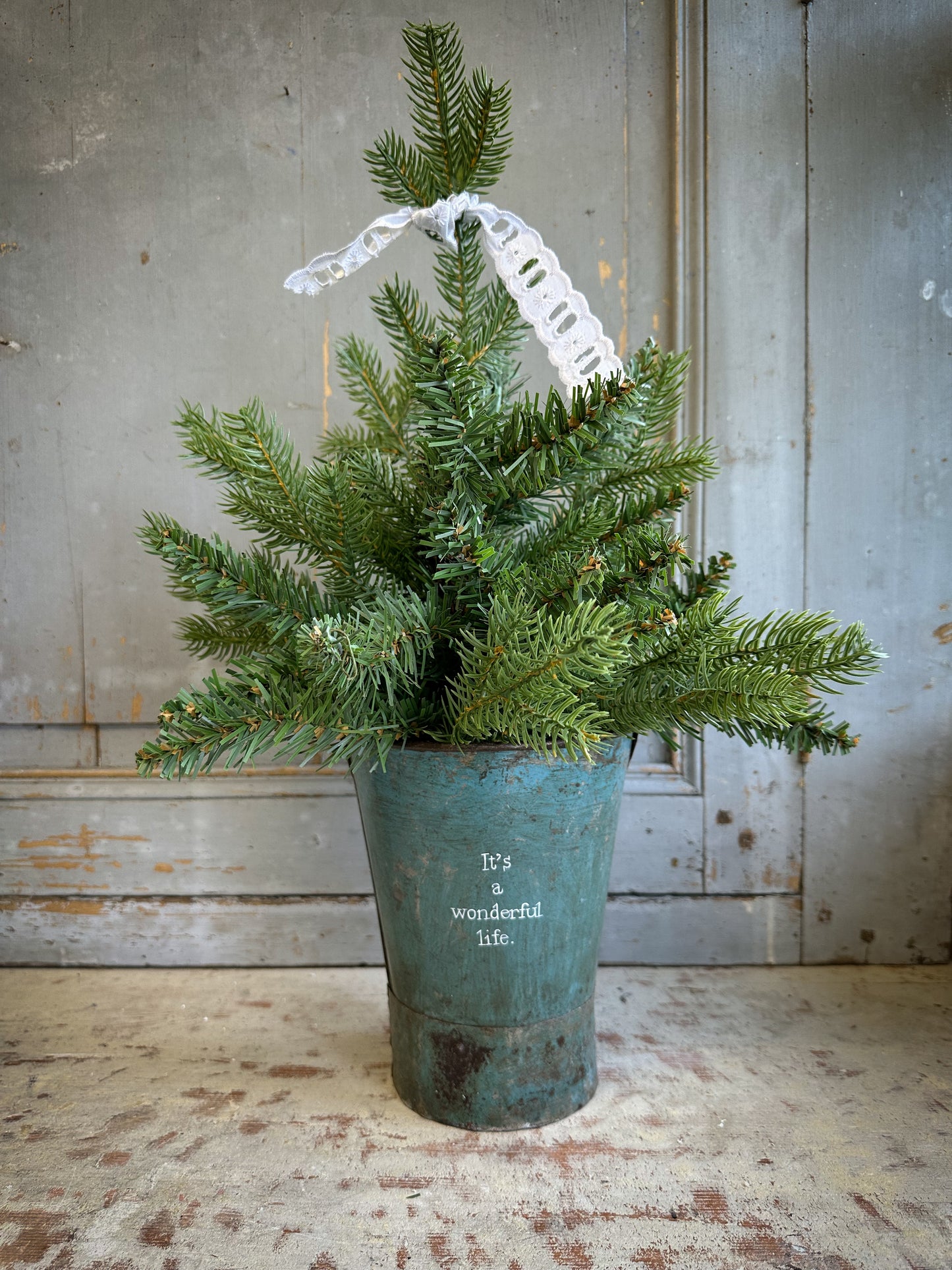 A Recycled Metal Mini Christmas Tree Bucket With A Hand Painted Quote