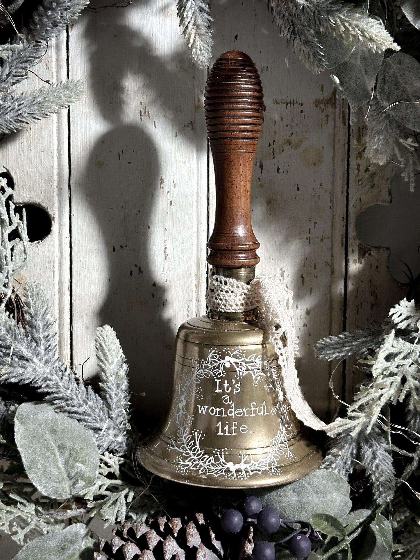 A vintage brass hand held bell with a hand painted quote