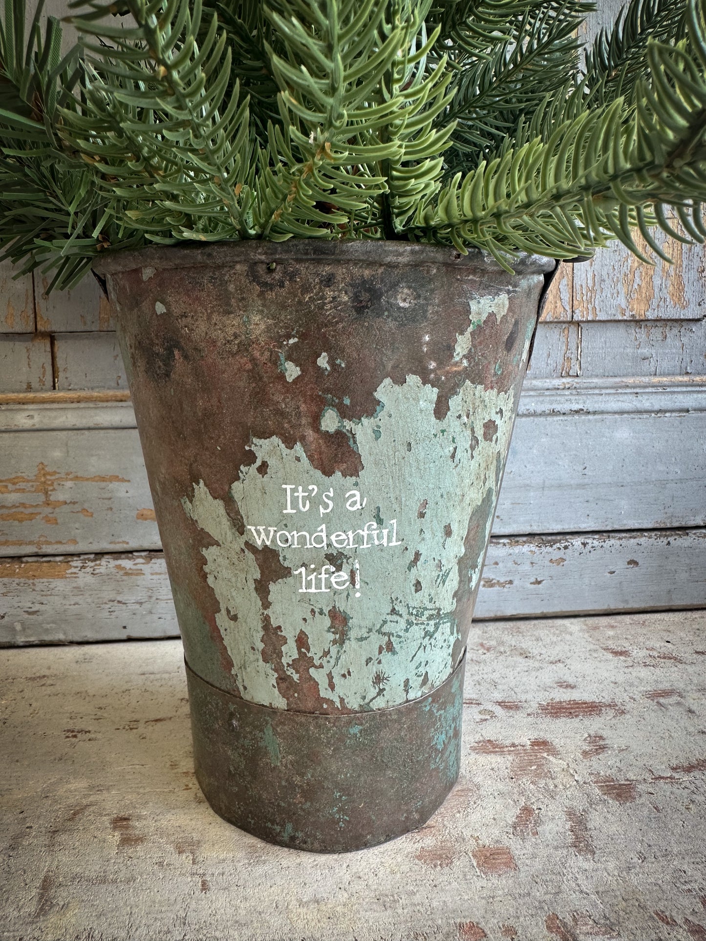 A Recycled Metal Mini Christmas Tree Bucket With A Hand Painted Quote