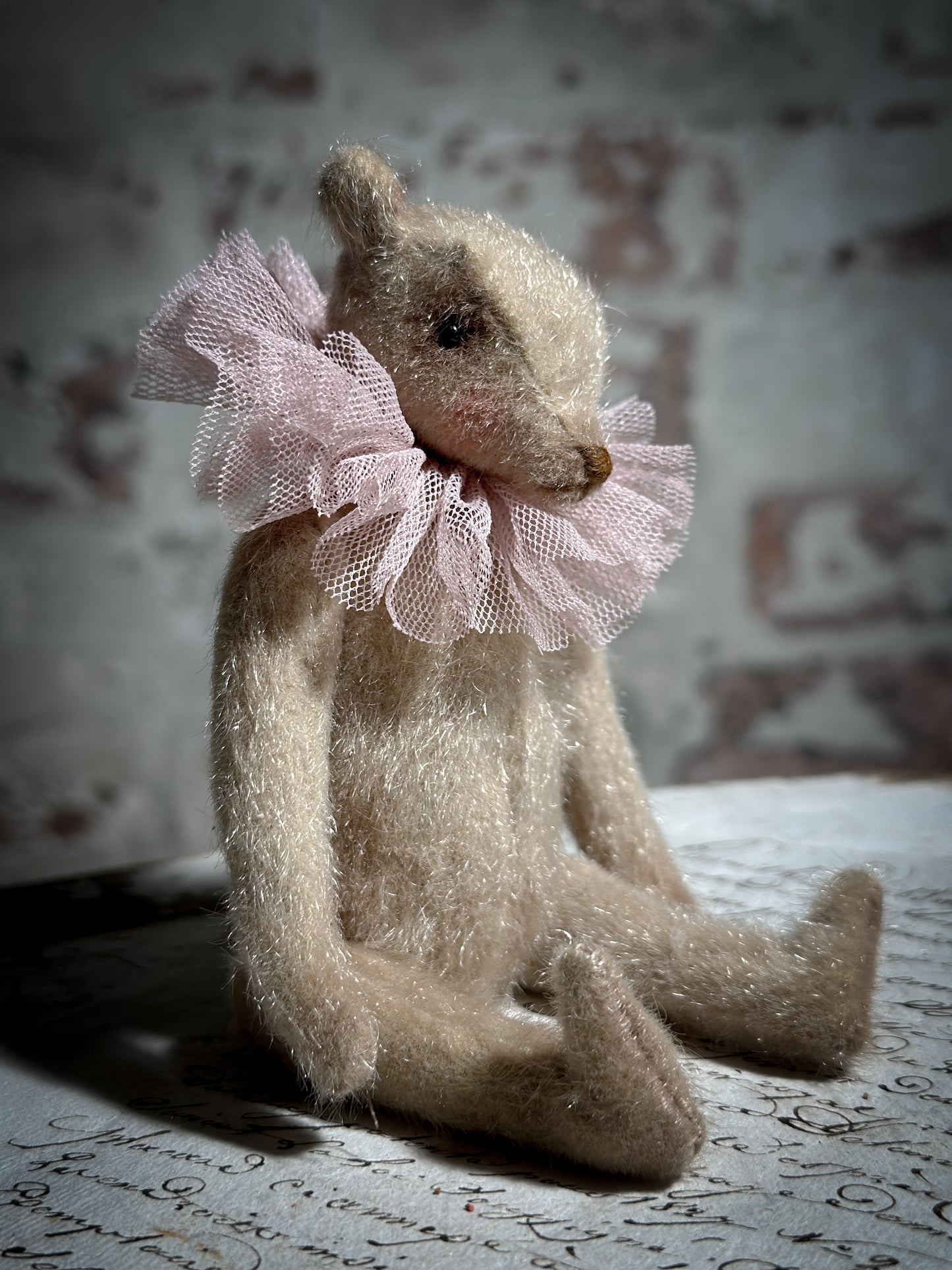 A beautiful hand made jointed collector’s teddy bear with antique pink tulle ruffle