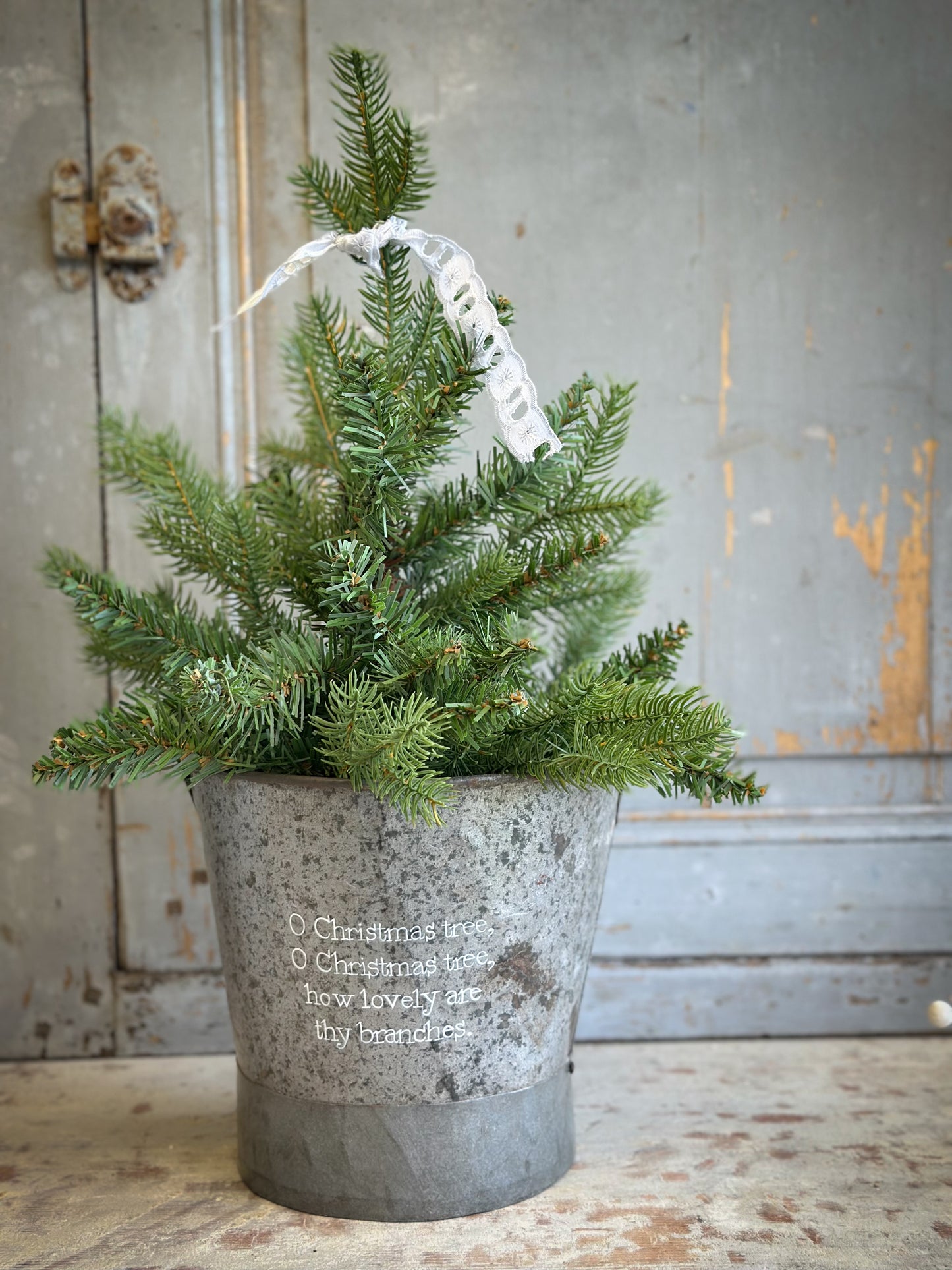 A Recycled Metal Small Christmas Tree Bucket With A Hand Painted Quote