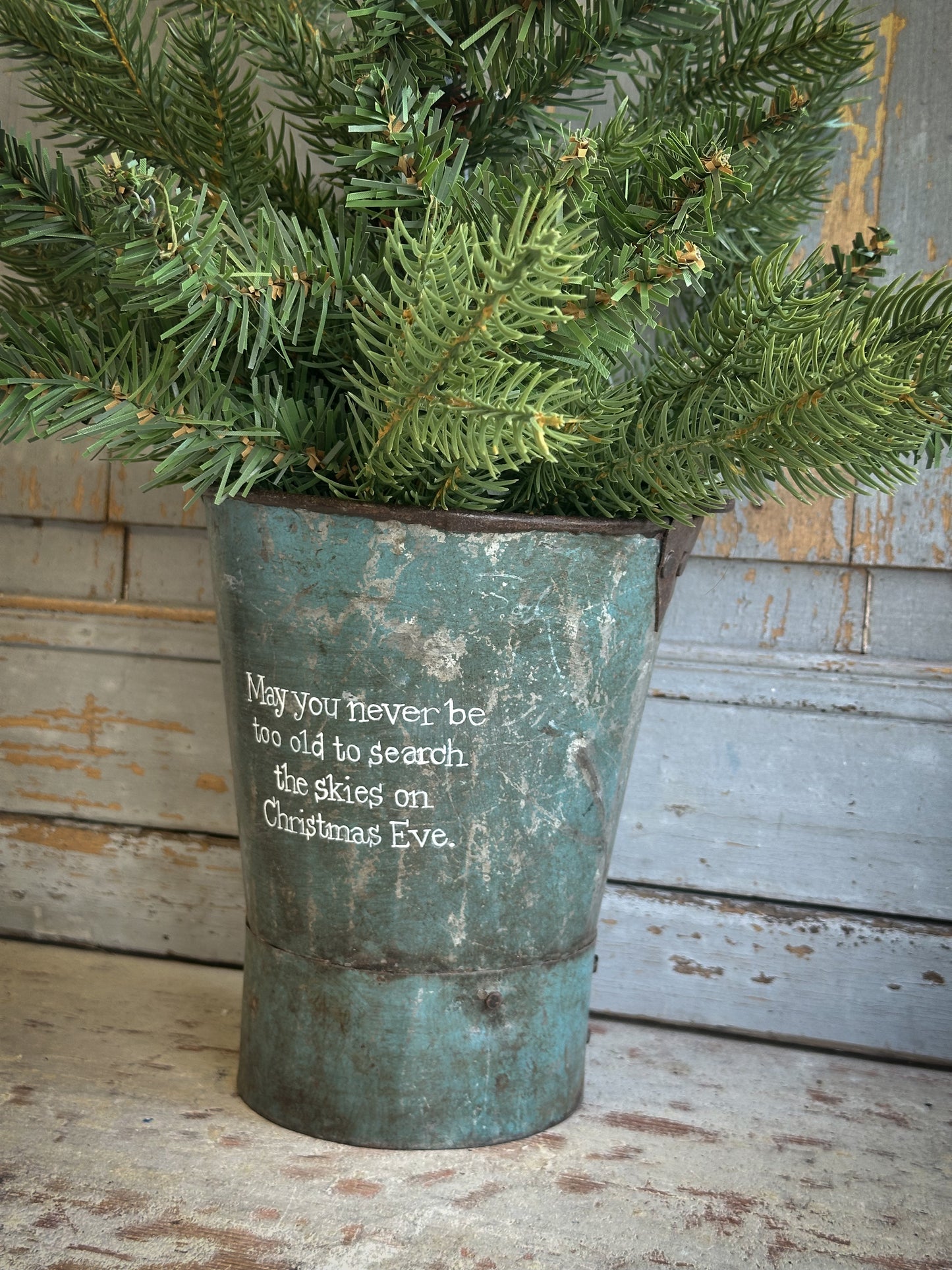 A Recycled Metal Mini Christmas Tree Bucket With A Hand Painted Quote