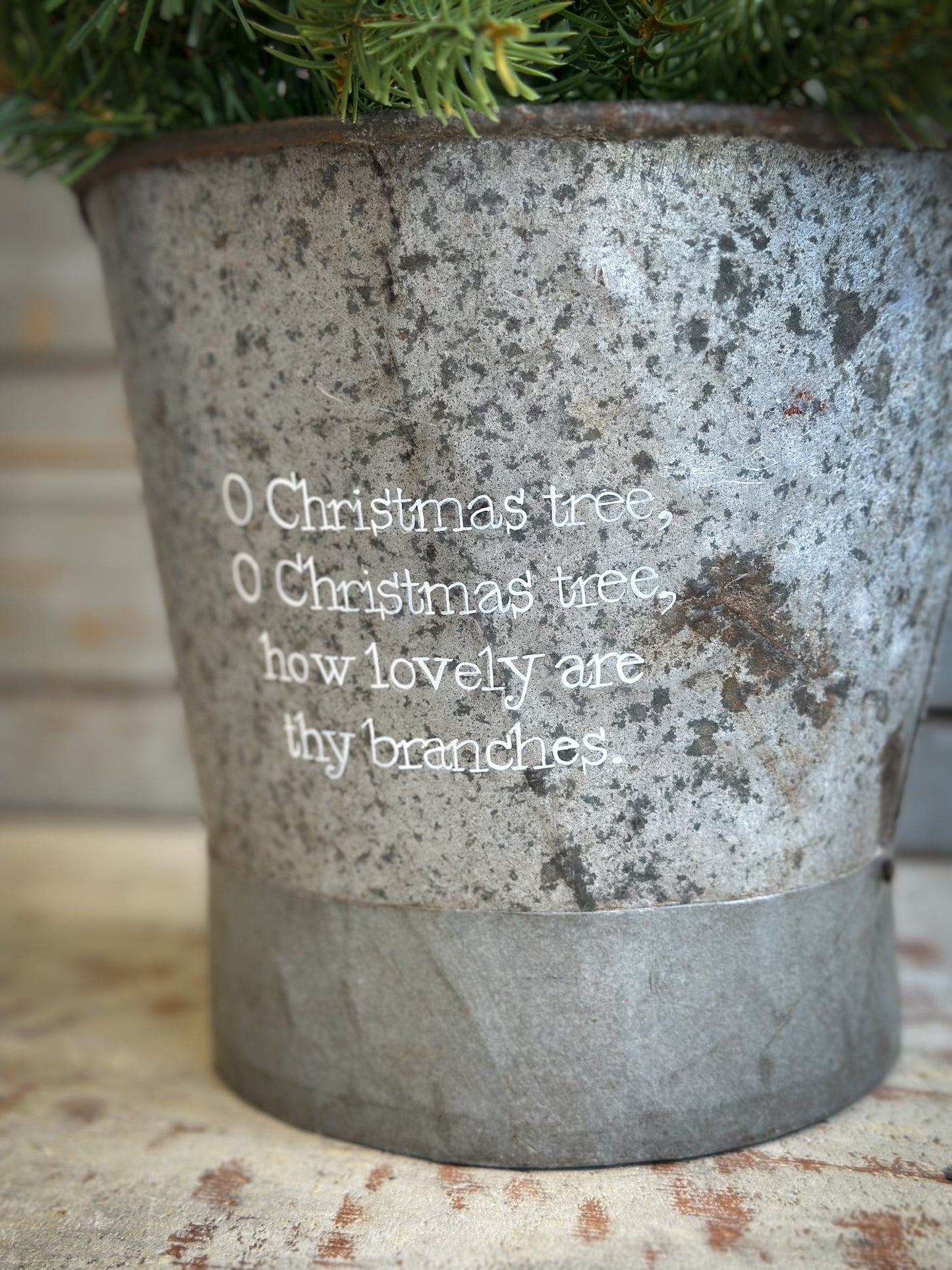 A Recycled Metal Small Christmas Tree Bucket With A Hand Painted Quote