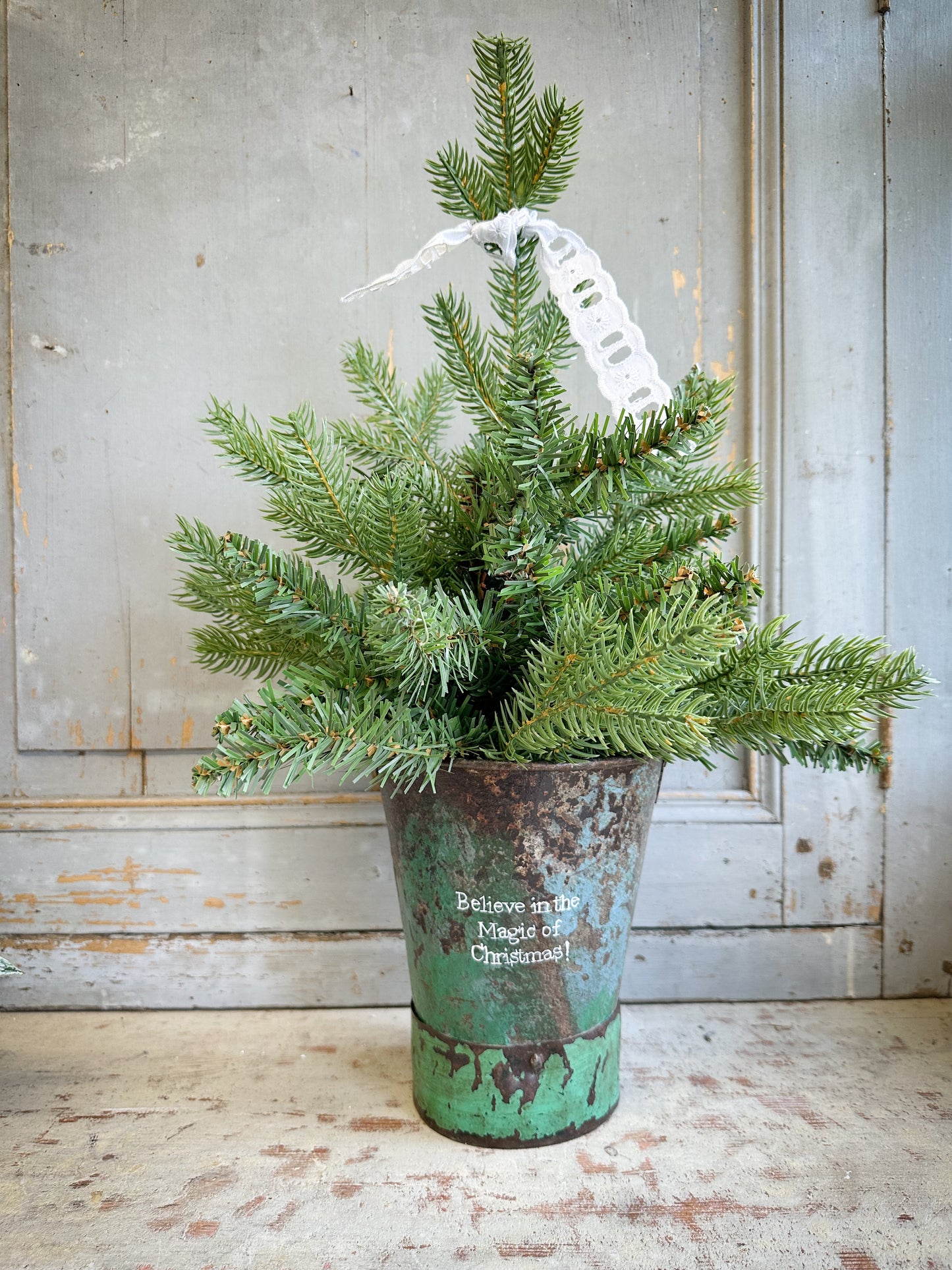 A Recycled Metal Mini Christmas Tree Bucket With A Hand Painted Quote