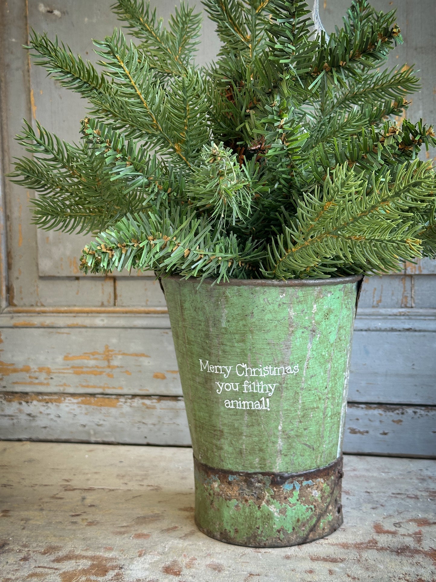 A Recycled Metal Mini Christmas Tree Bucket With A Hand Painted Quote