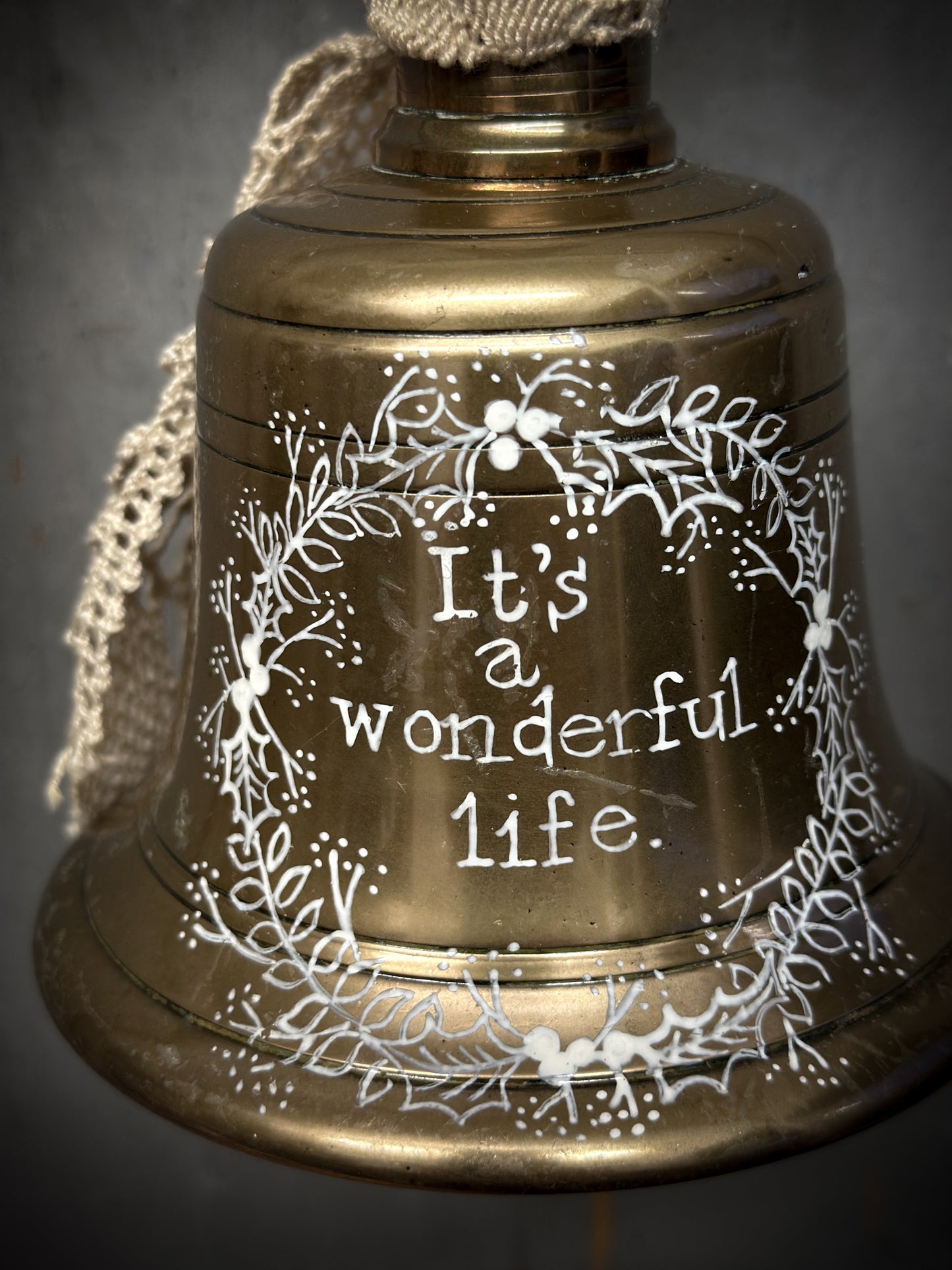 A vintage brass hand held bell with a hand painted quote