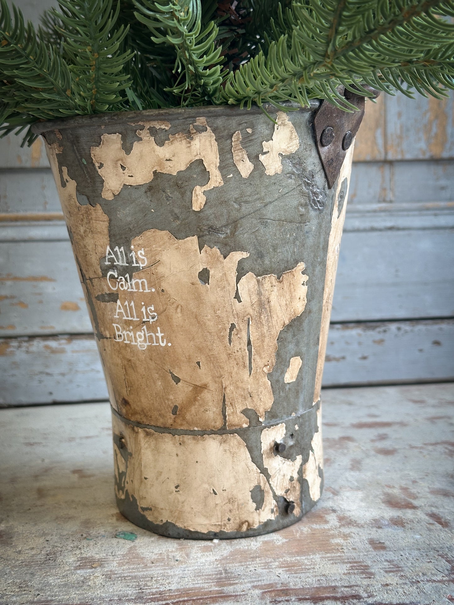 A Recycled Metal Mini Christmas Tree Bucket With A Hand Painted Quote
